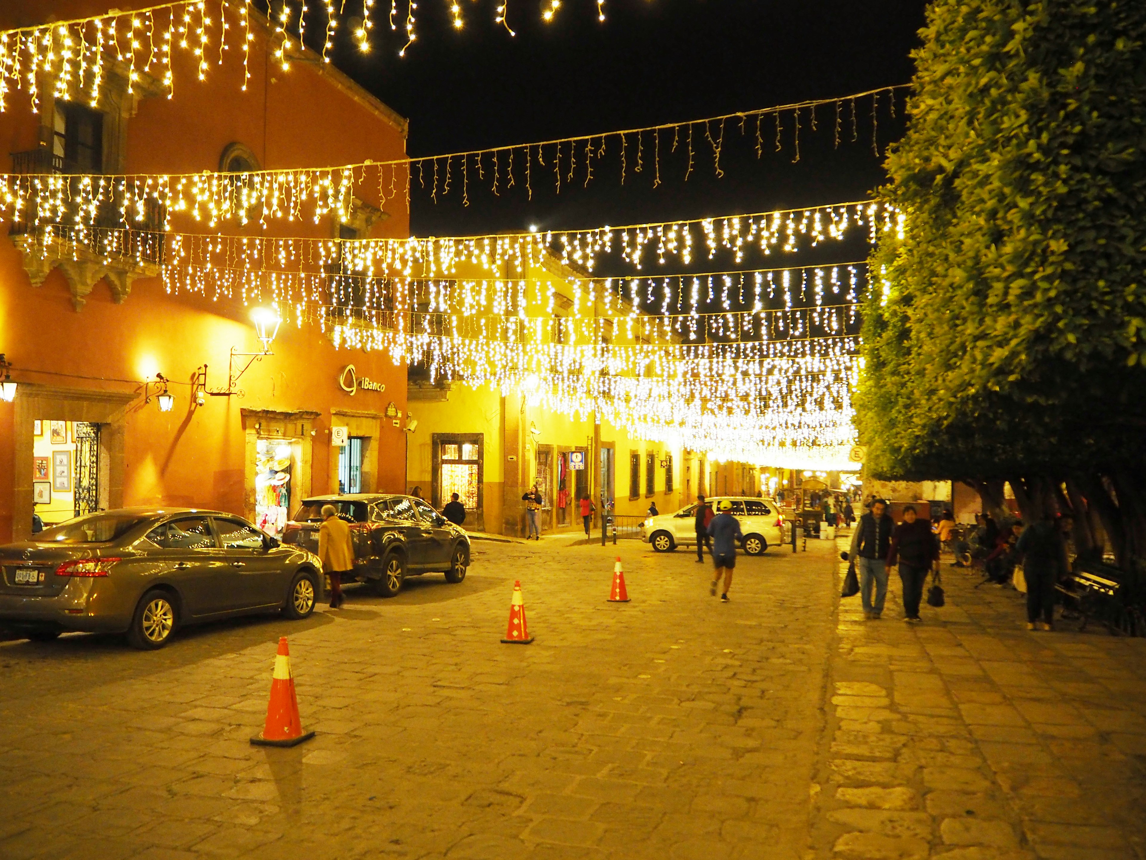 Una calle vibrante adornada con luces festivas y personas por la noche