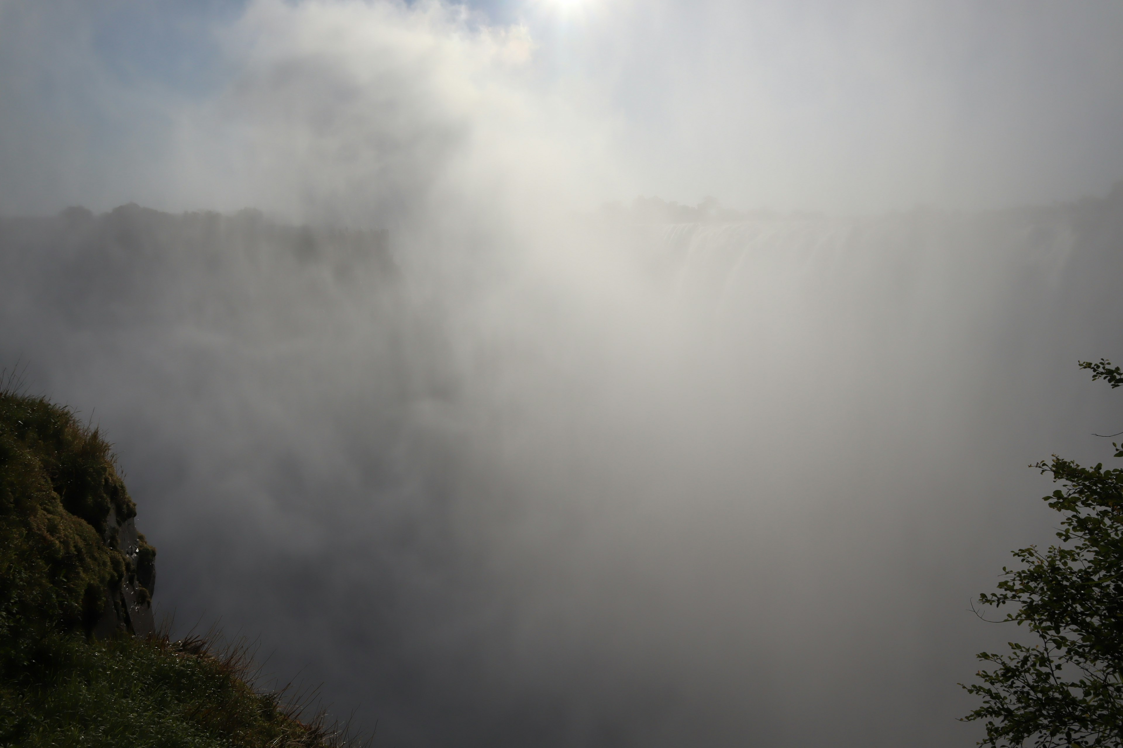 Misty view of a waterfall surrounded by lush greenery and dramatic cliffs