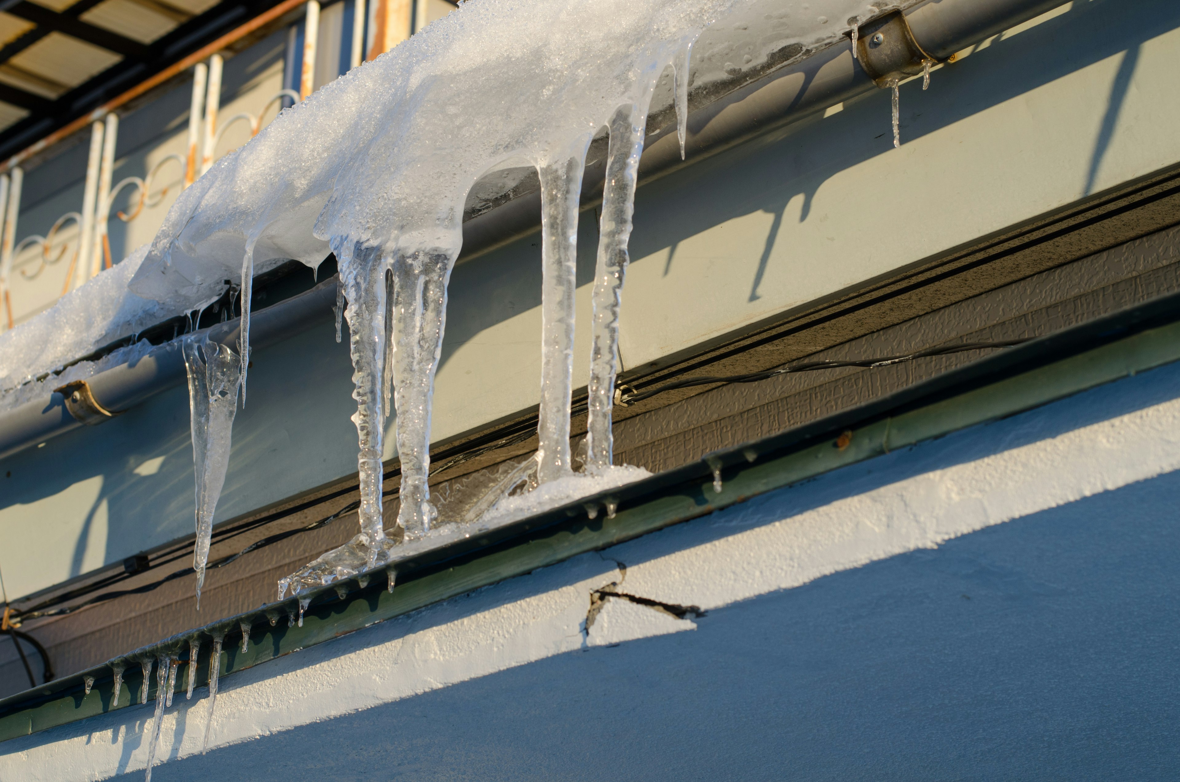 Eiszapfen und Eisformationen, die von einem schneebedeckten Dach hängen