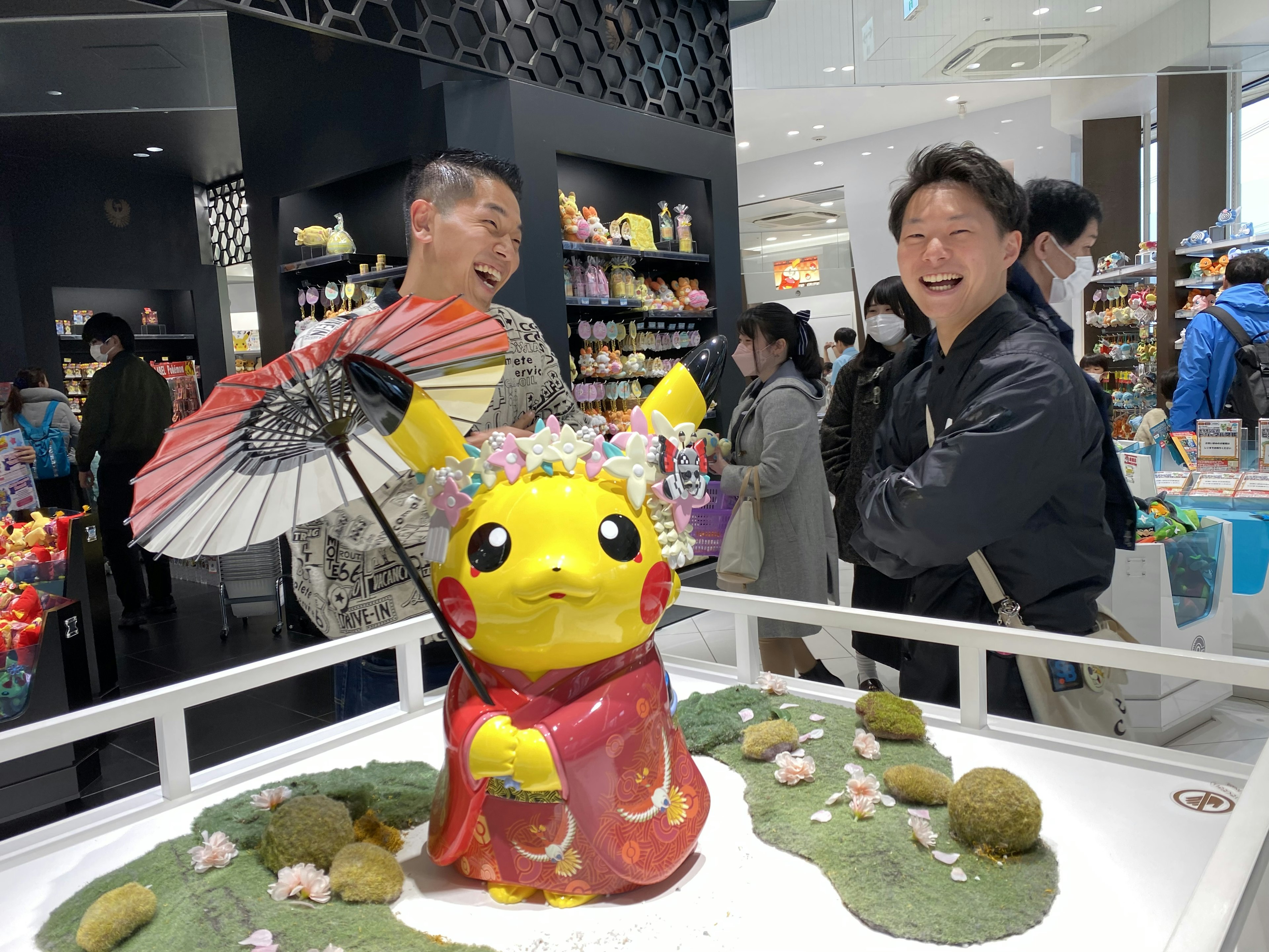 ピカチュウの着物を着た像と笑顔の人々がいる風景