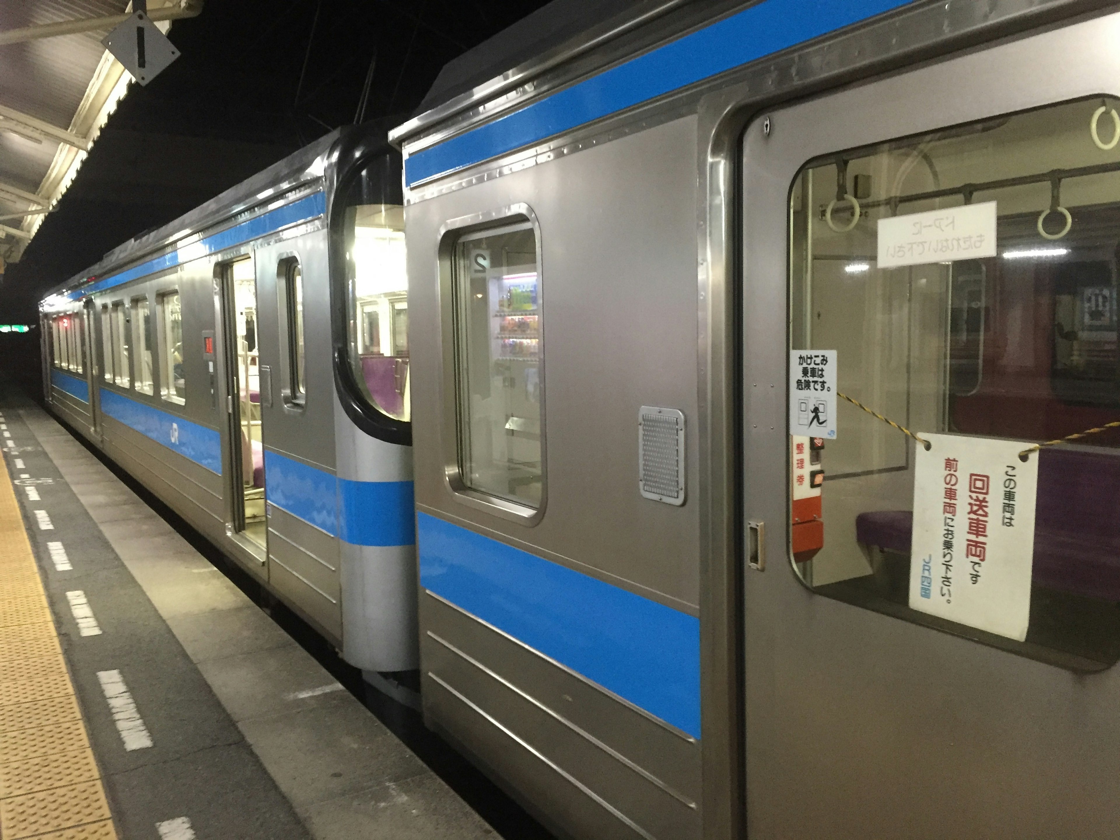 Tren plateado con rayas azules en una estación por la noche