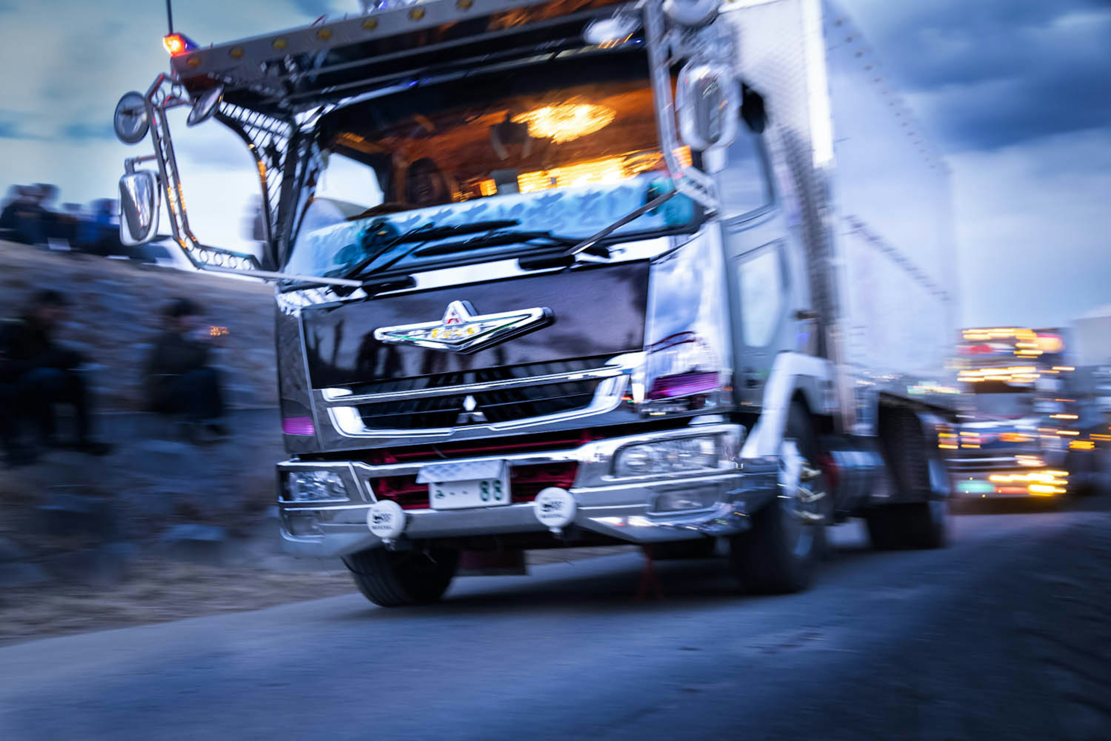 A truck speeding down a road at night with a blurred background