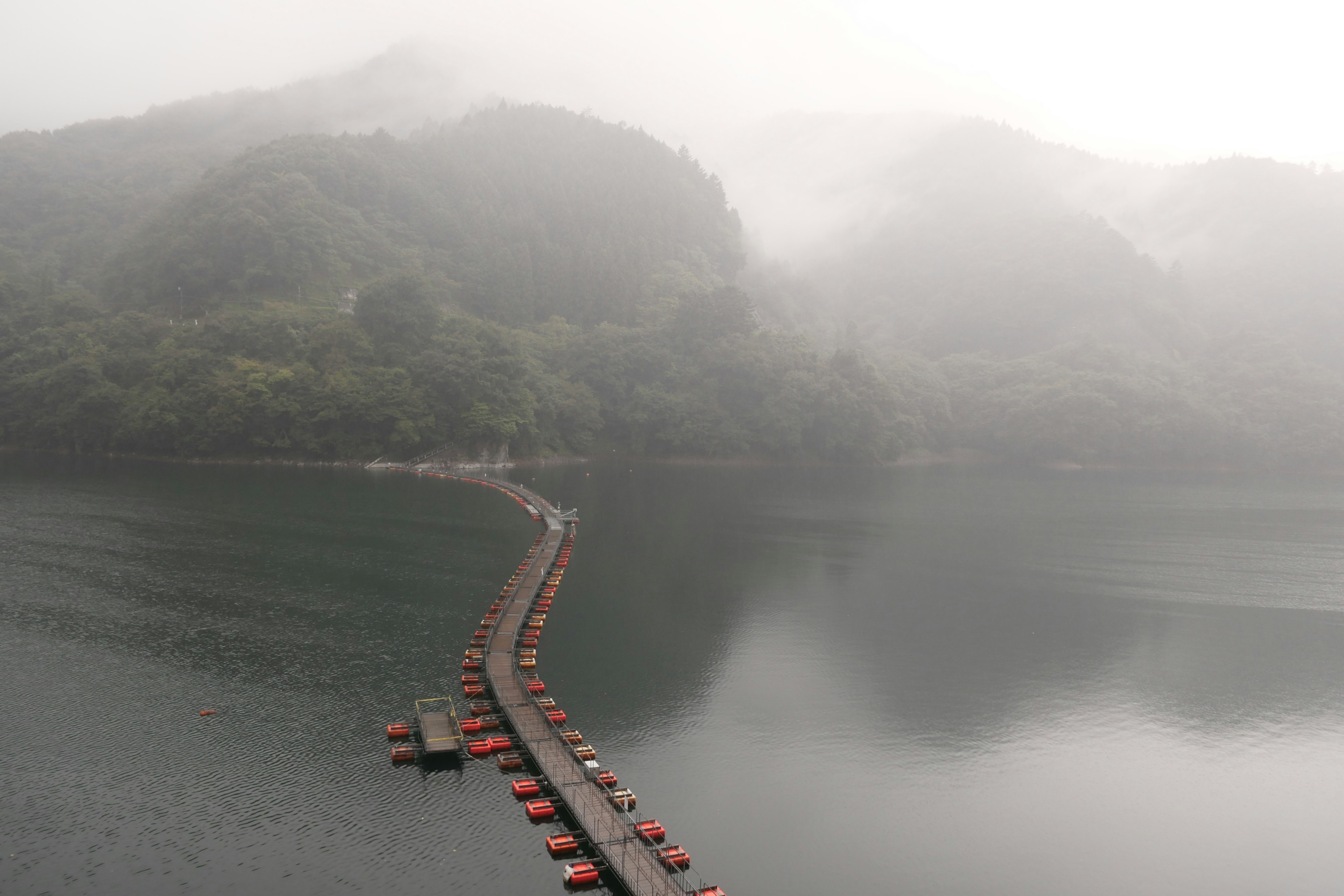 Foggy lake scene with a winding red pontoon bridge