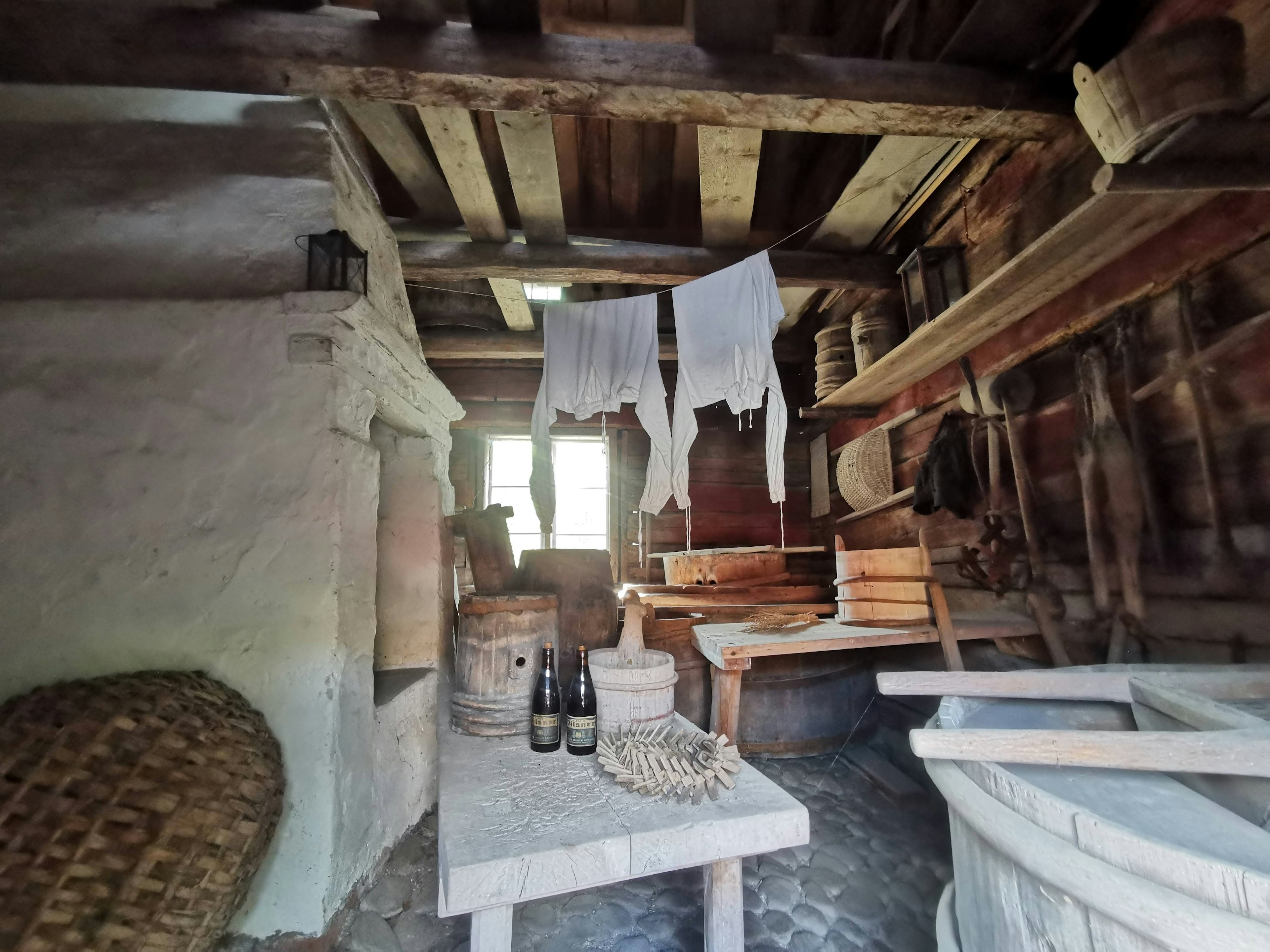 Intérieur d'une ancienne ferme avec des étagères et une table en bois et de la lumière naturelle