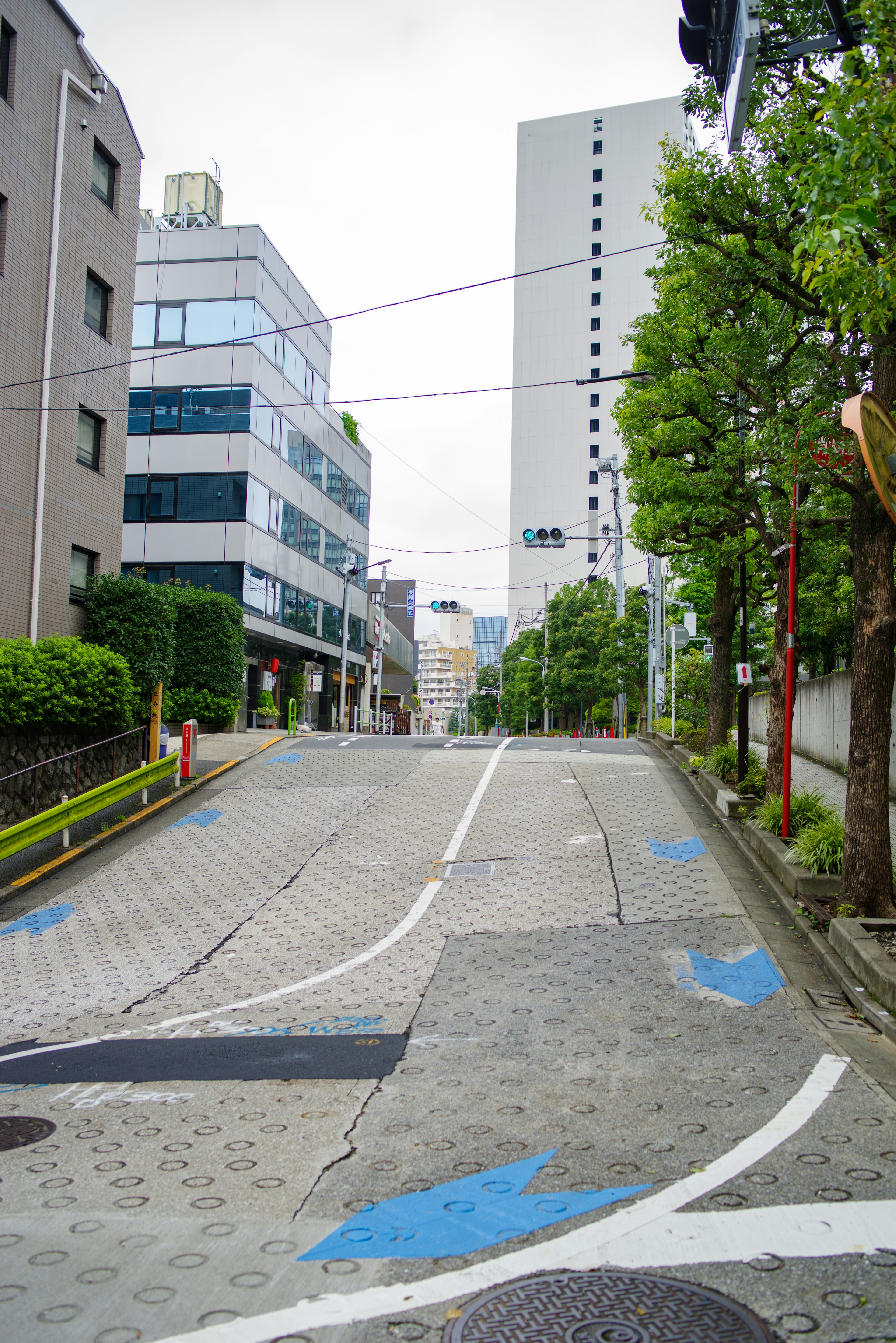 A sloped street with blue arrows visible buildings and green trees lining the road