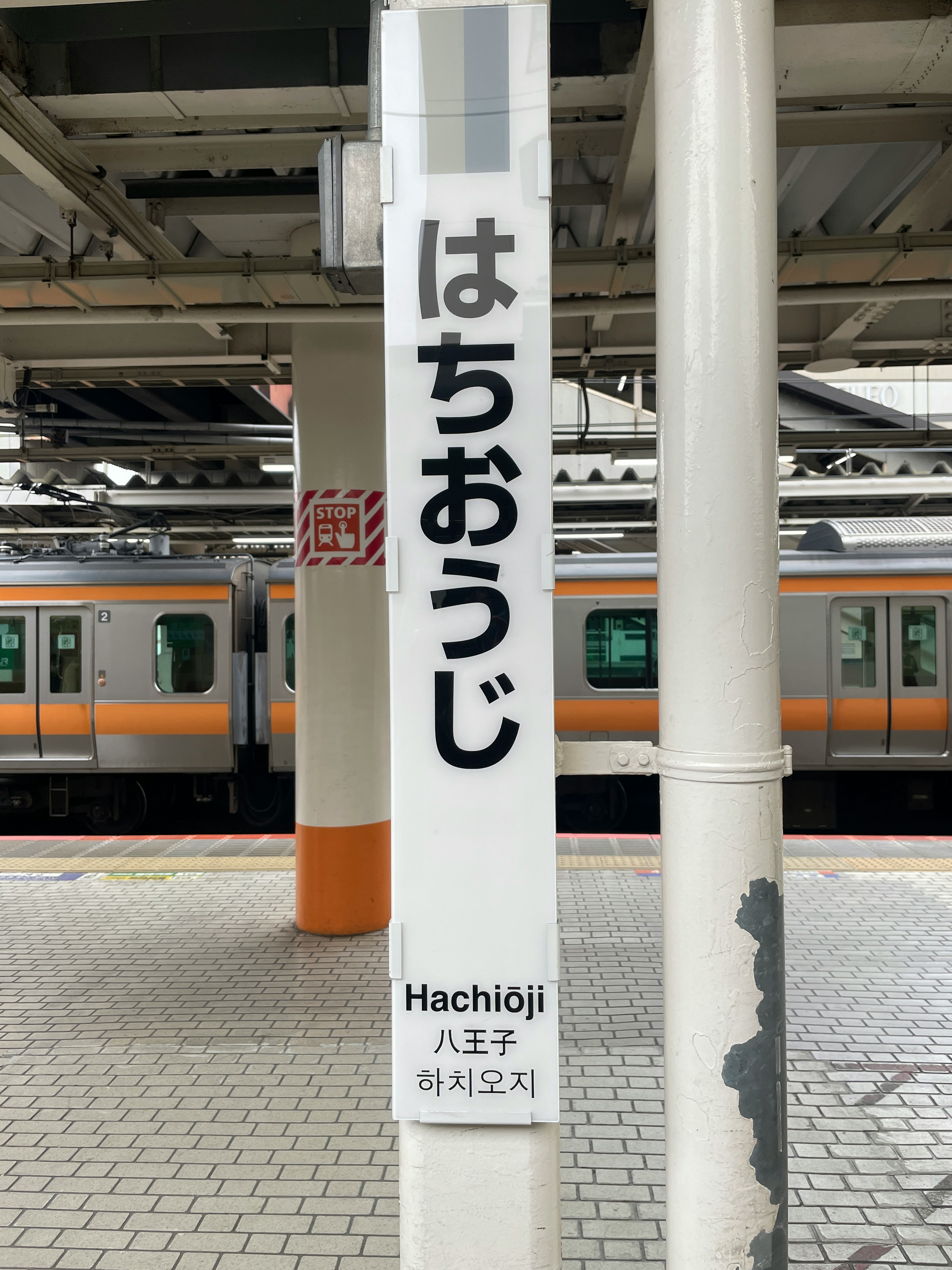 八王子駅の看板と電車の一部が見える駅の風景