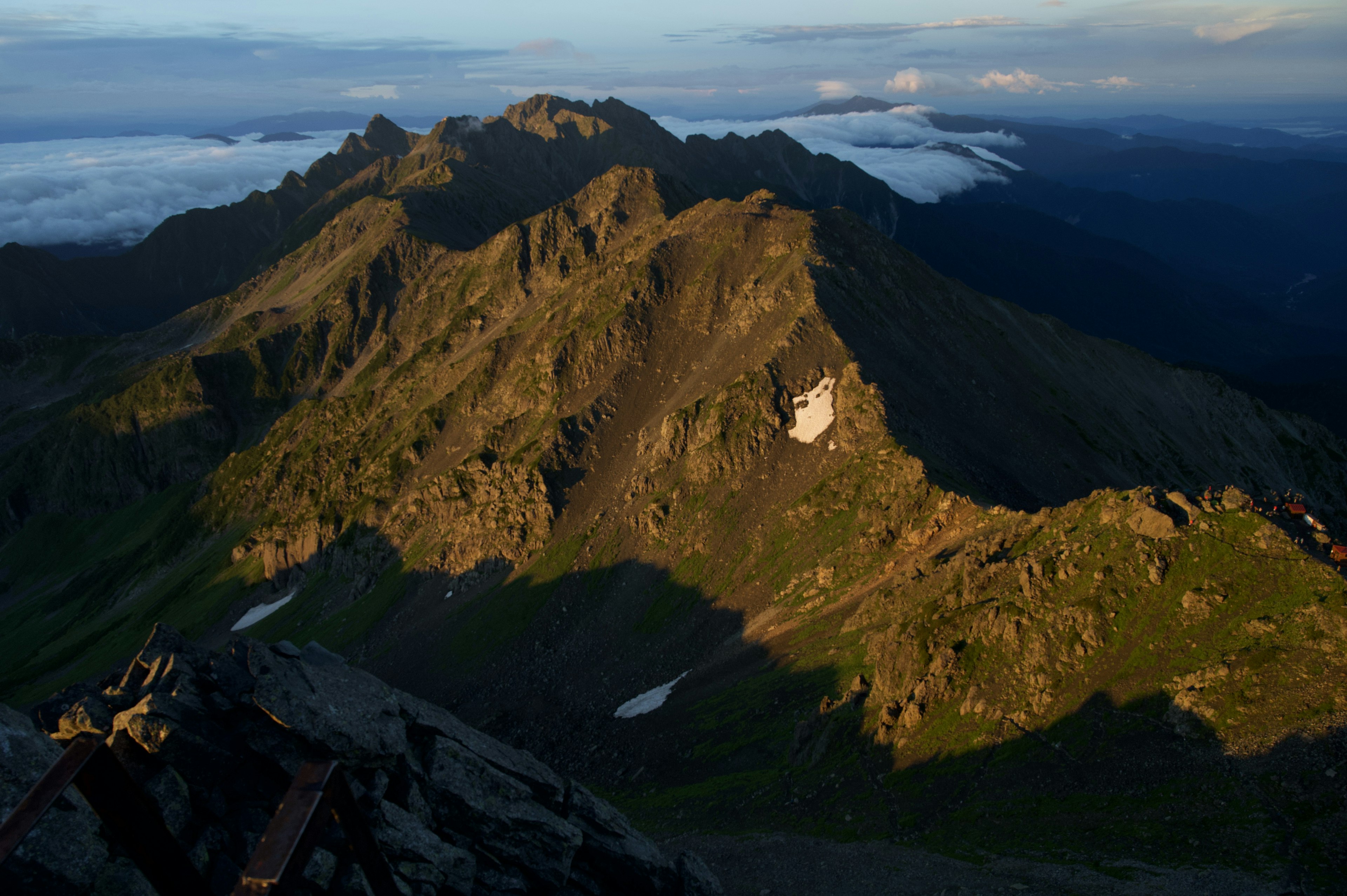 Stunning view from a mountain peak showcasing green valleys and rocky formations with a sea of clouds in the background