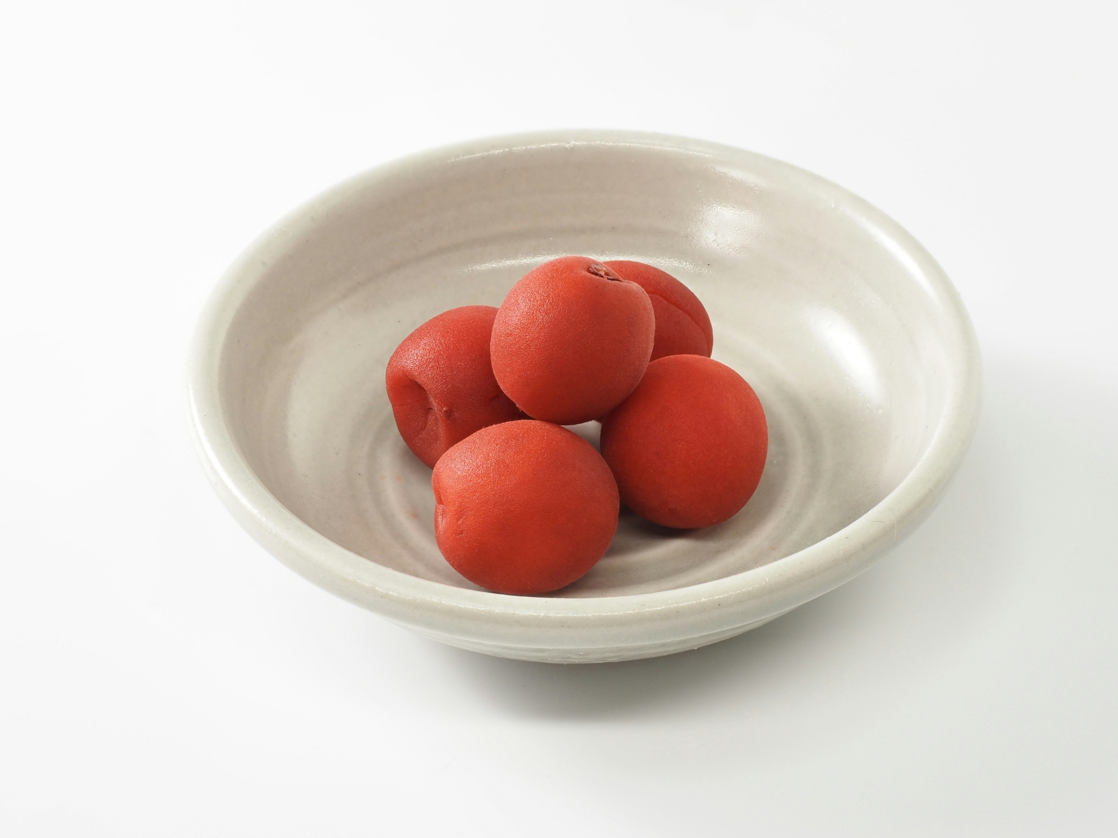 Six red balls arranged in a white dish