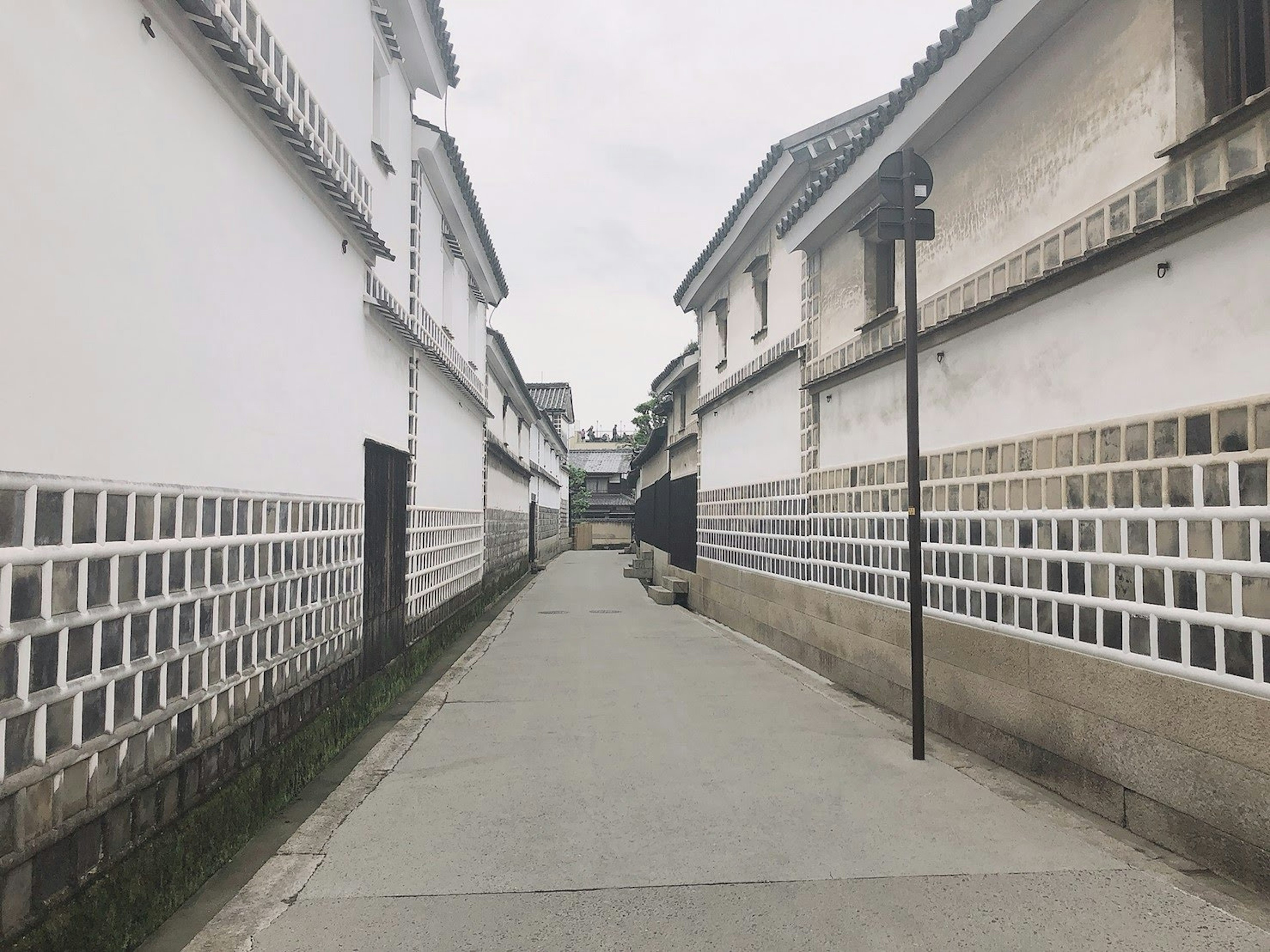 Quiet street lined with white walls and stone pavement