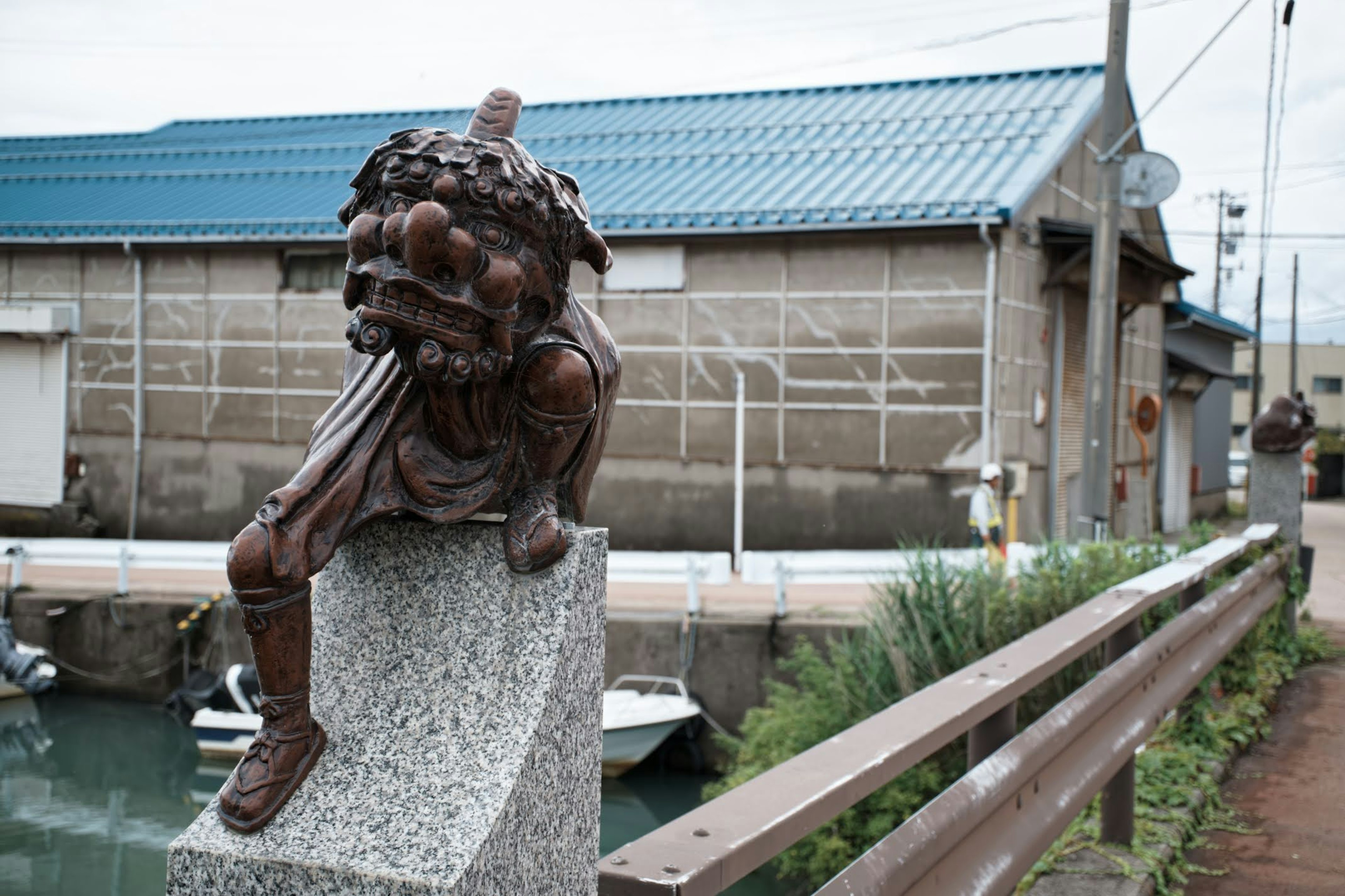 Sculpture d'une figure avec une tête de lion près d'un bâtiment à toit bleu