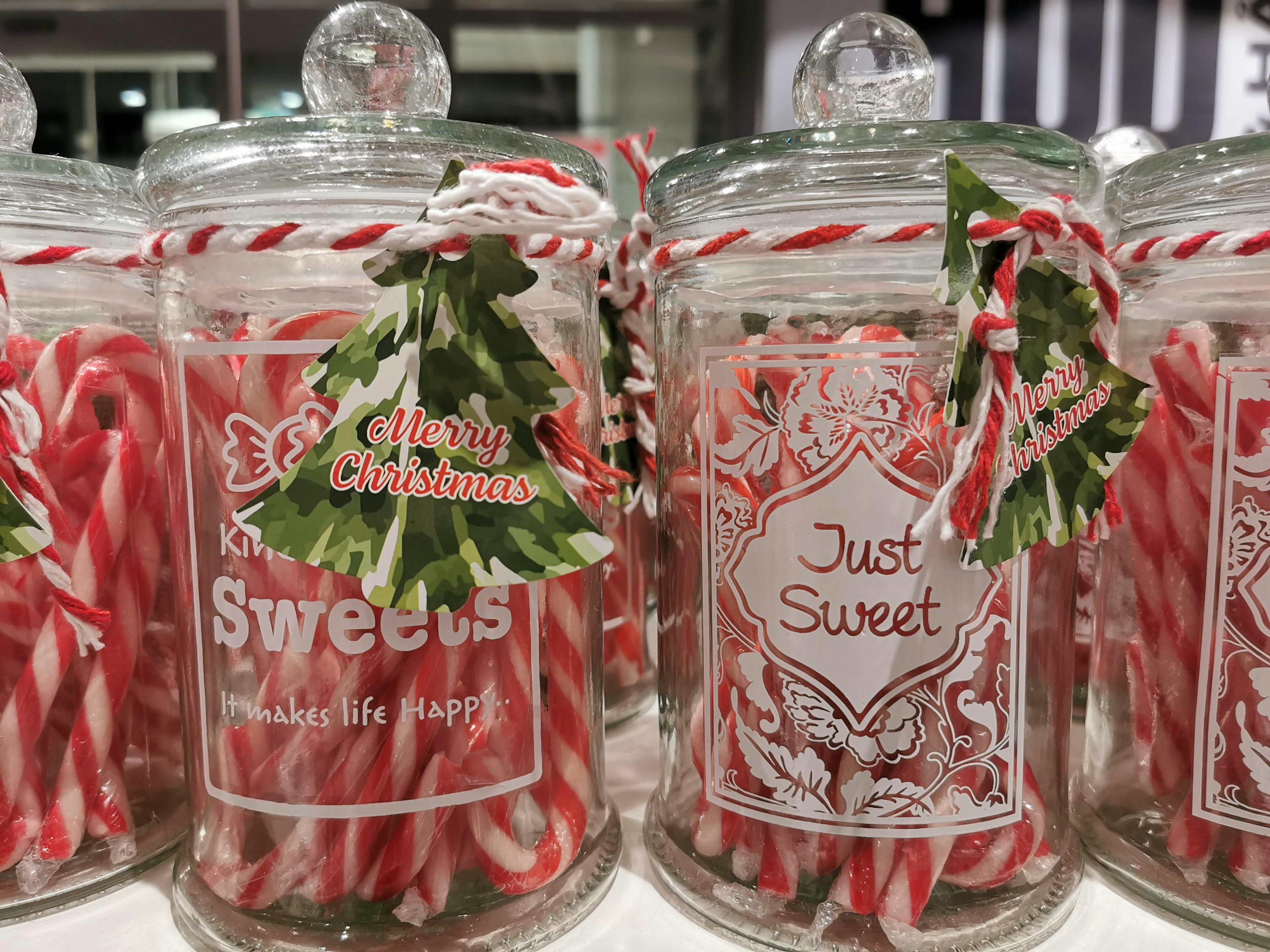 Glass jars filled with red and white candy canes decorated with festive tags