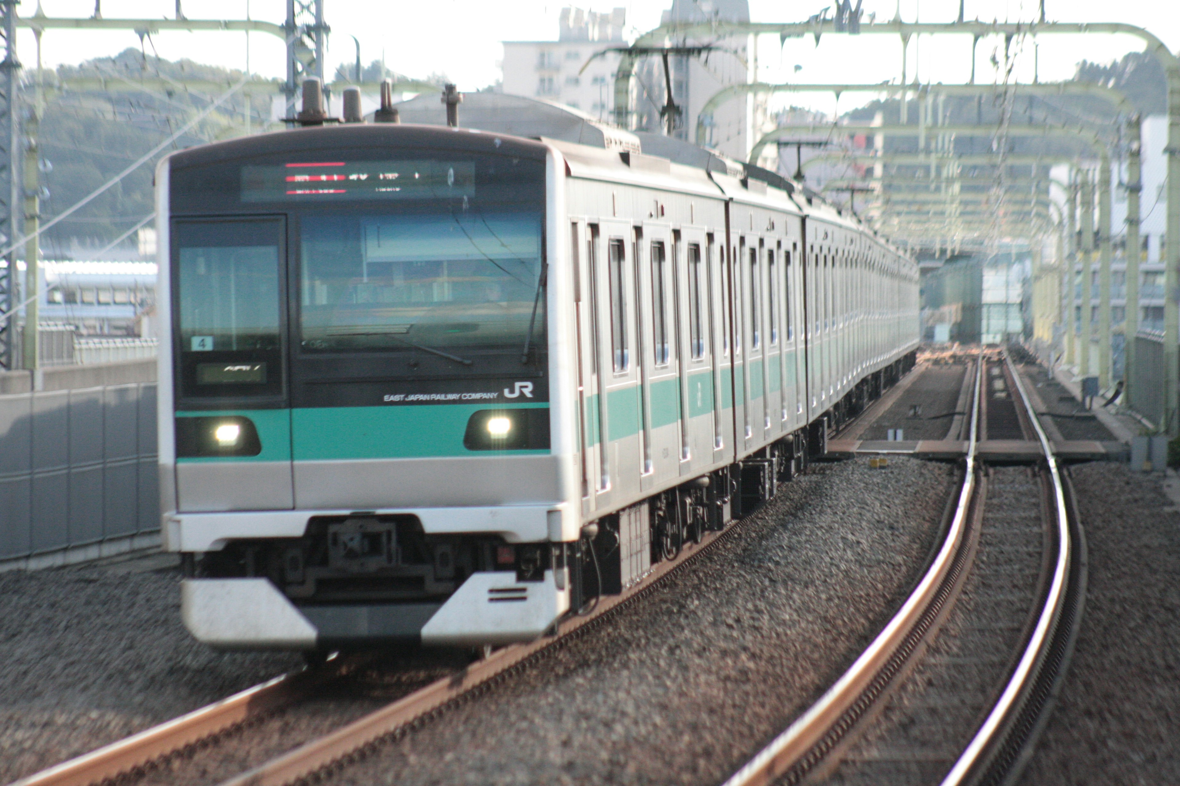 Train argenté avec une bande verte qui tourne sur les rails