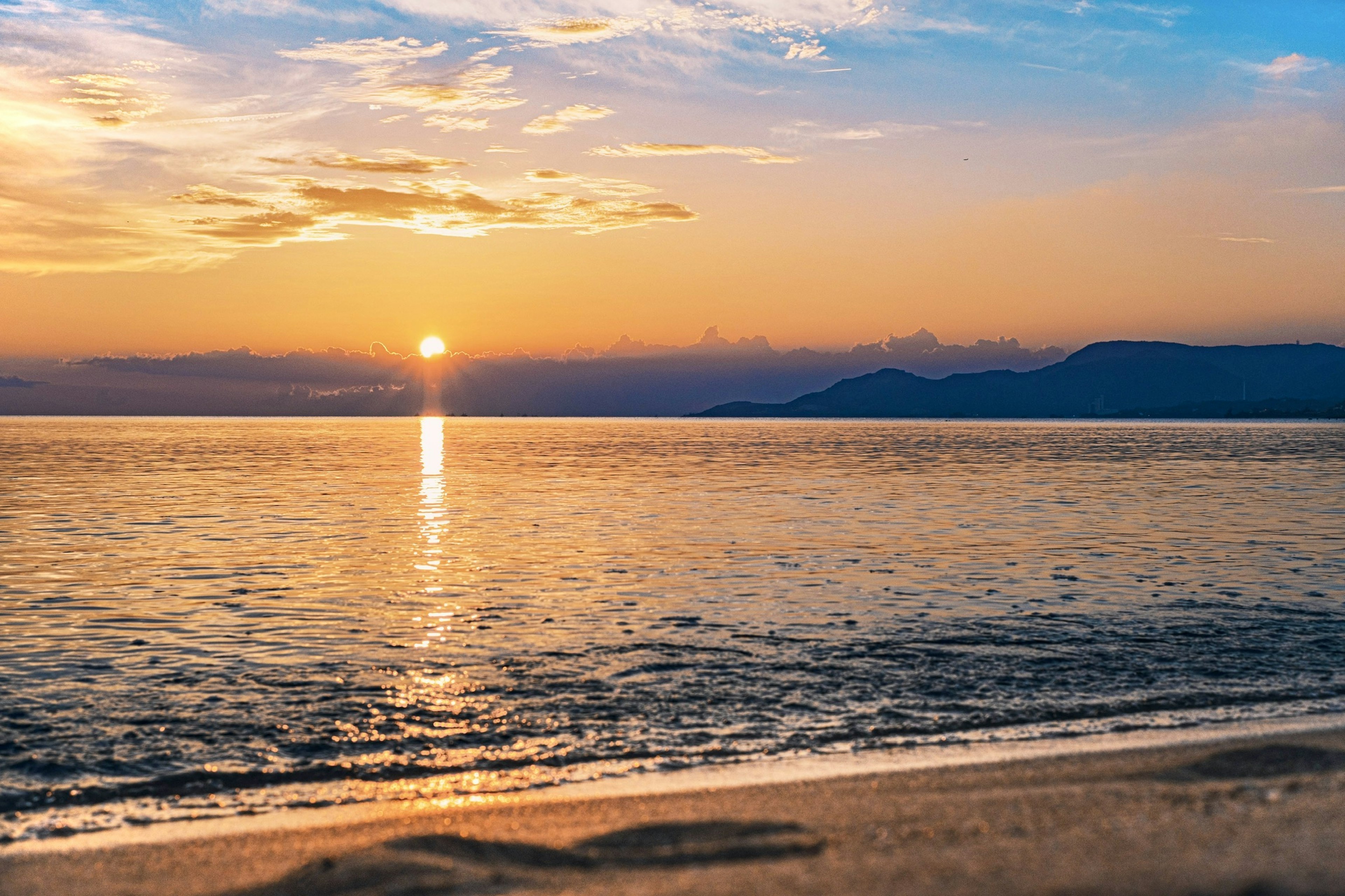 Magnifique paysage marin avec le coucher de soleil se reflétant sur l'eau et des vagues douces