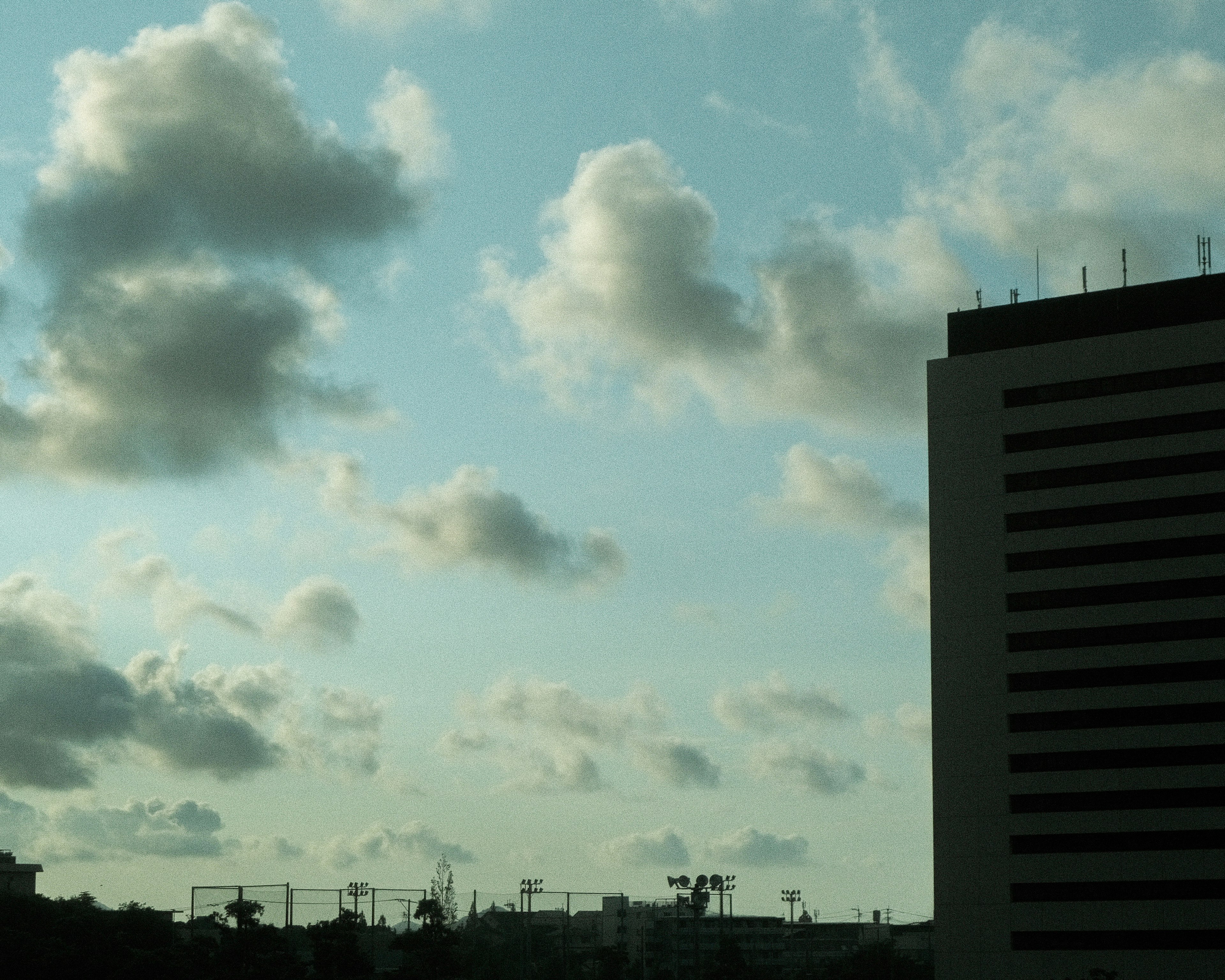 Cielo con nubes y un edificio alto en primer plano