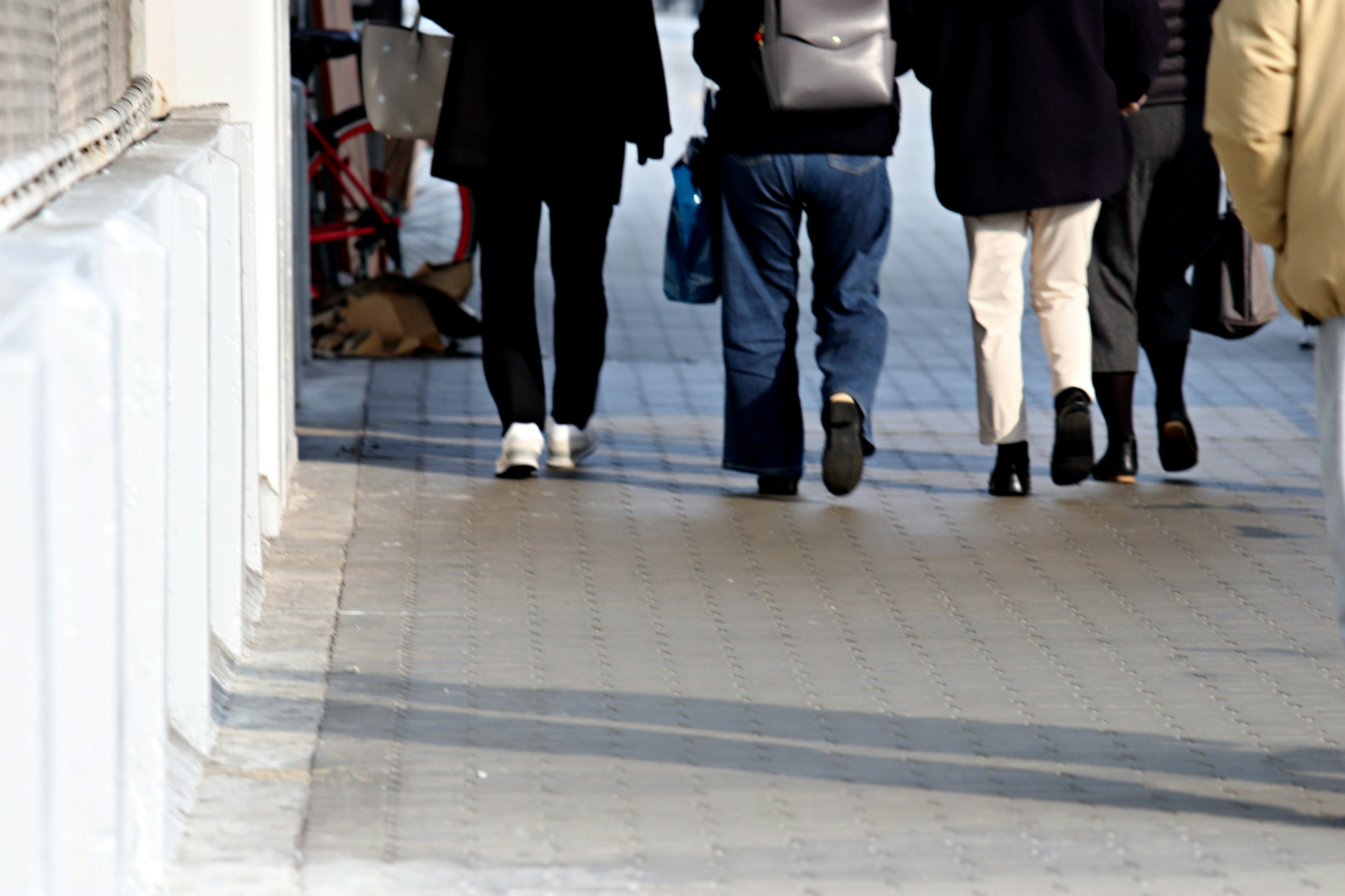 People walking on a sidewalk seen from behind