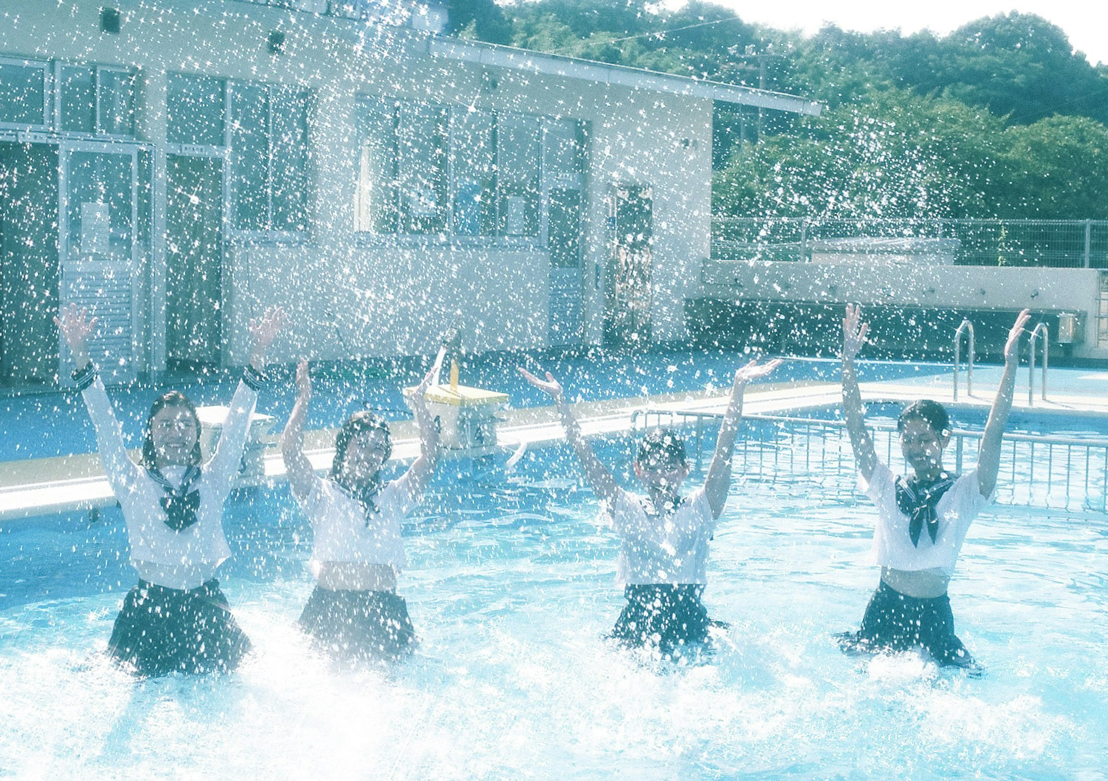 Cuatro chicas salpicando agua en una piscina