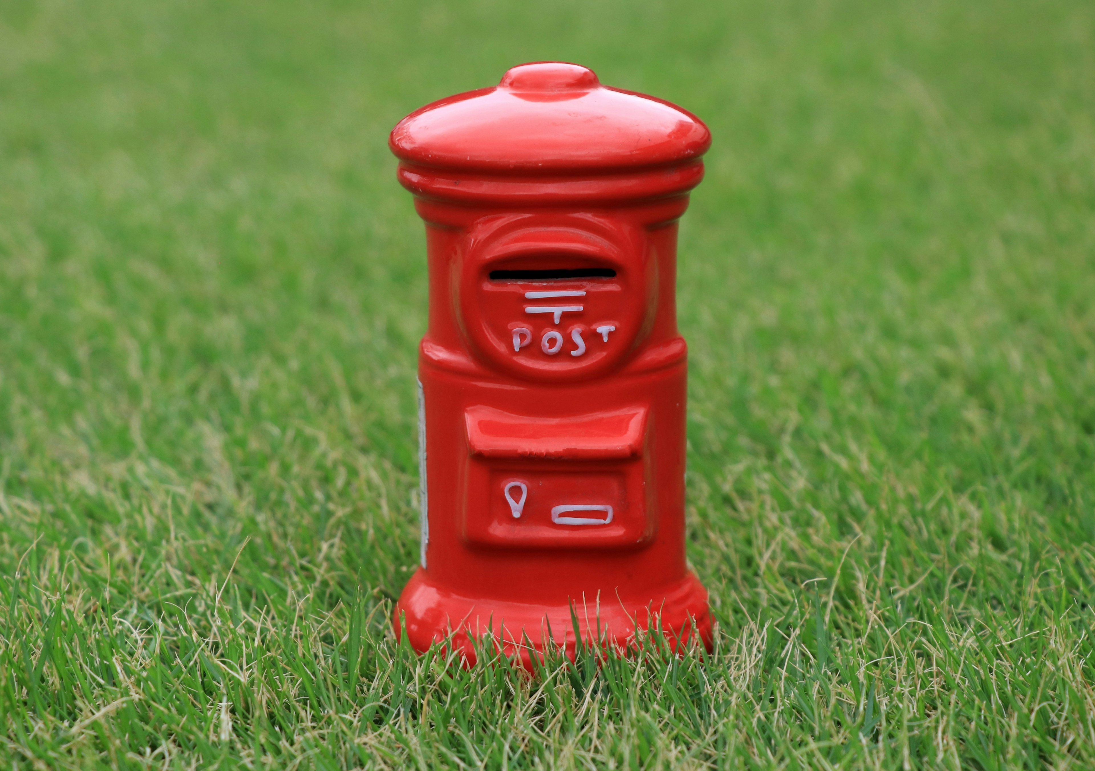 A red mailbox standing on green grass