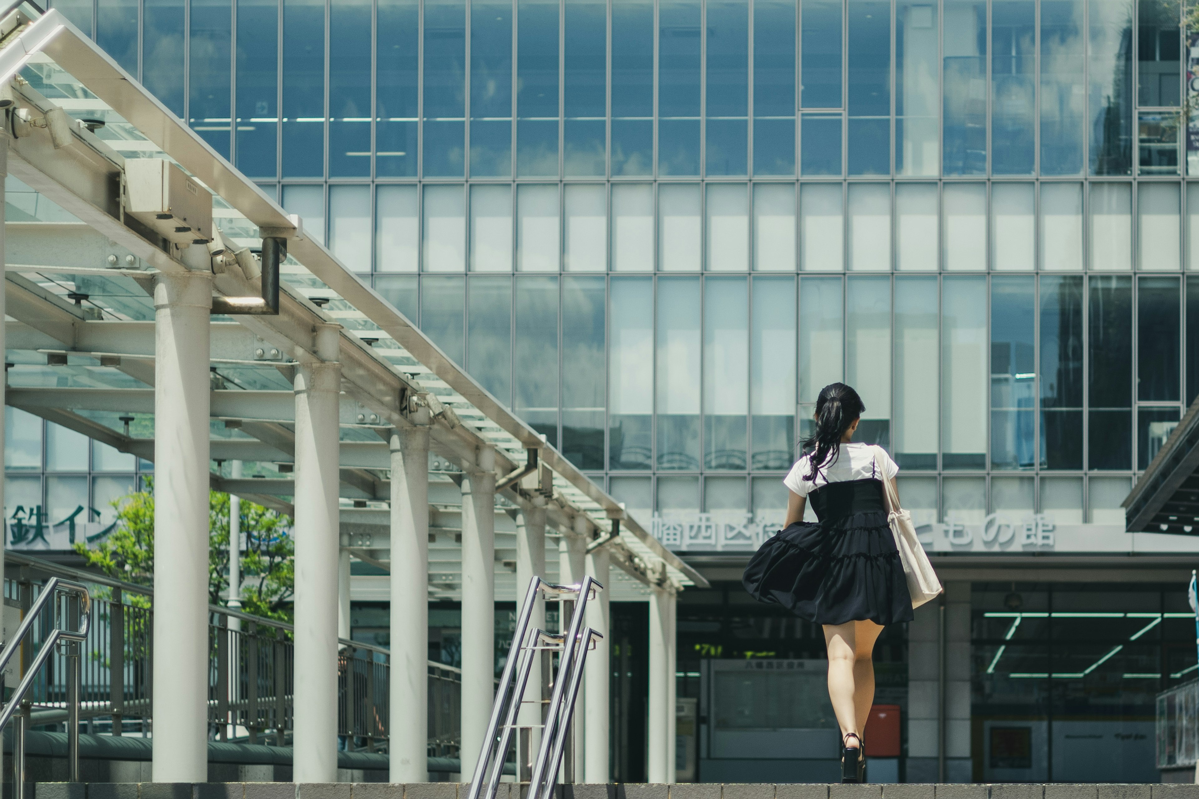 黒いドレスを着た女性が現代的な建物の前を歩いている