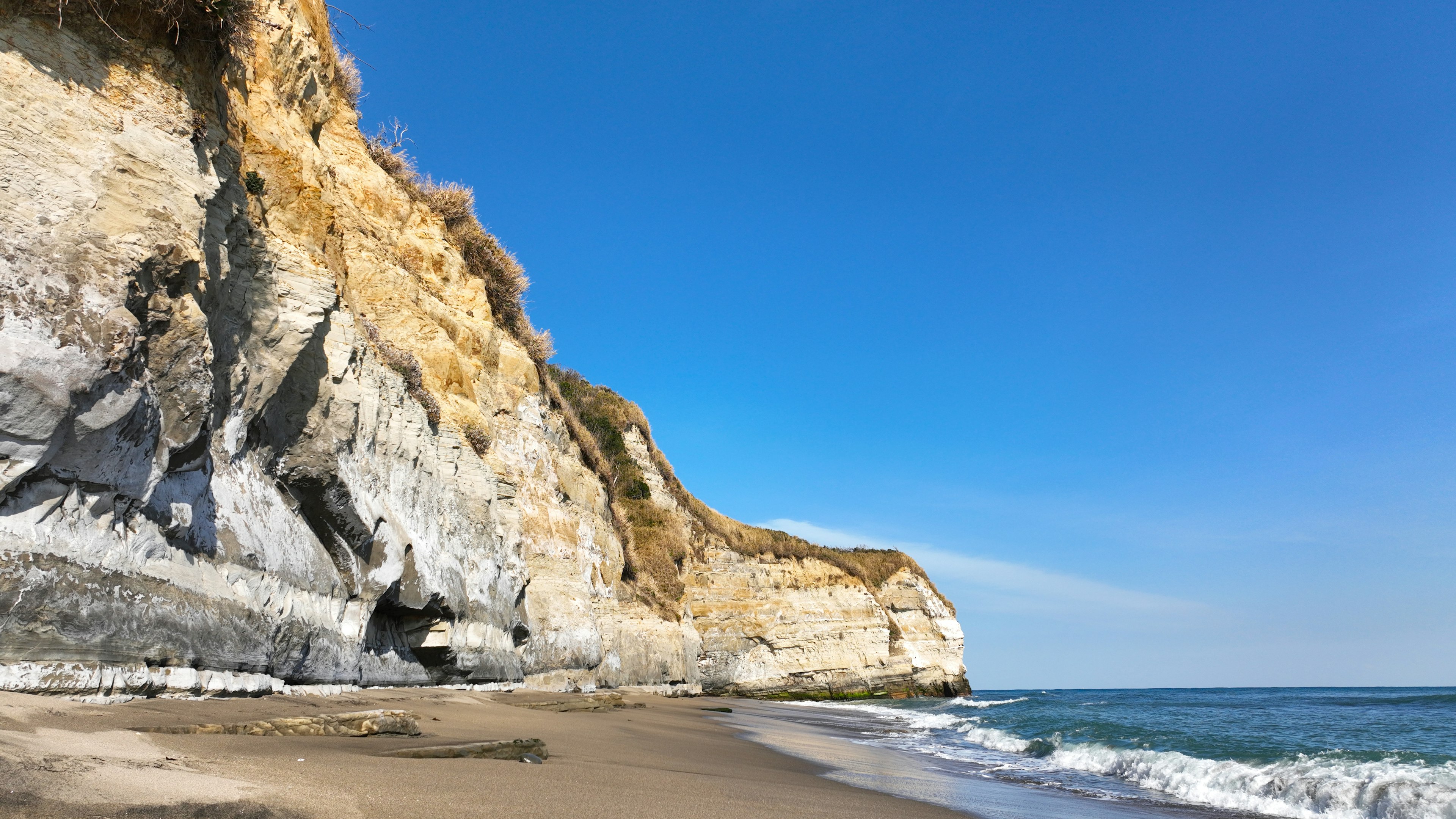 Tebing pantai dengan langit biru dan pantai berpasir