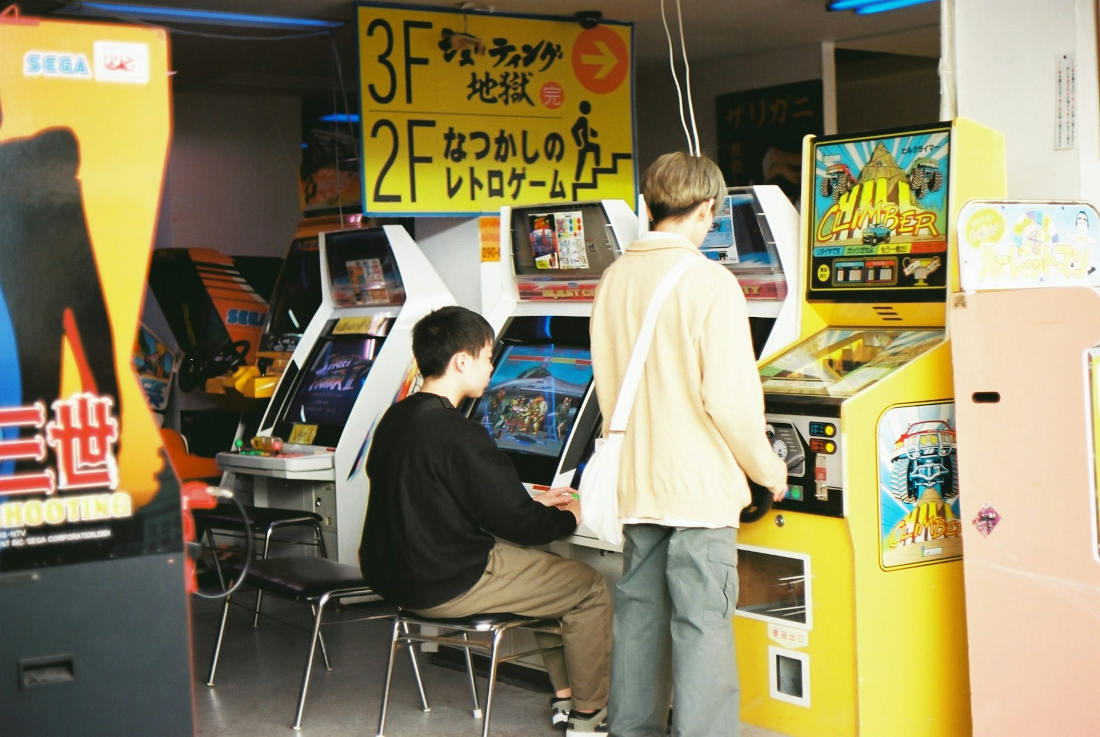 Two young men playing arcade games in a game center