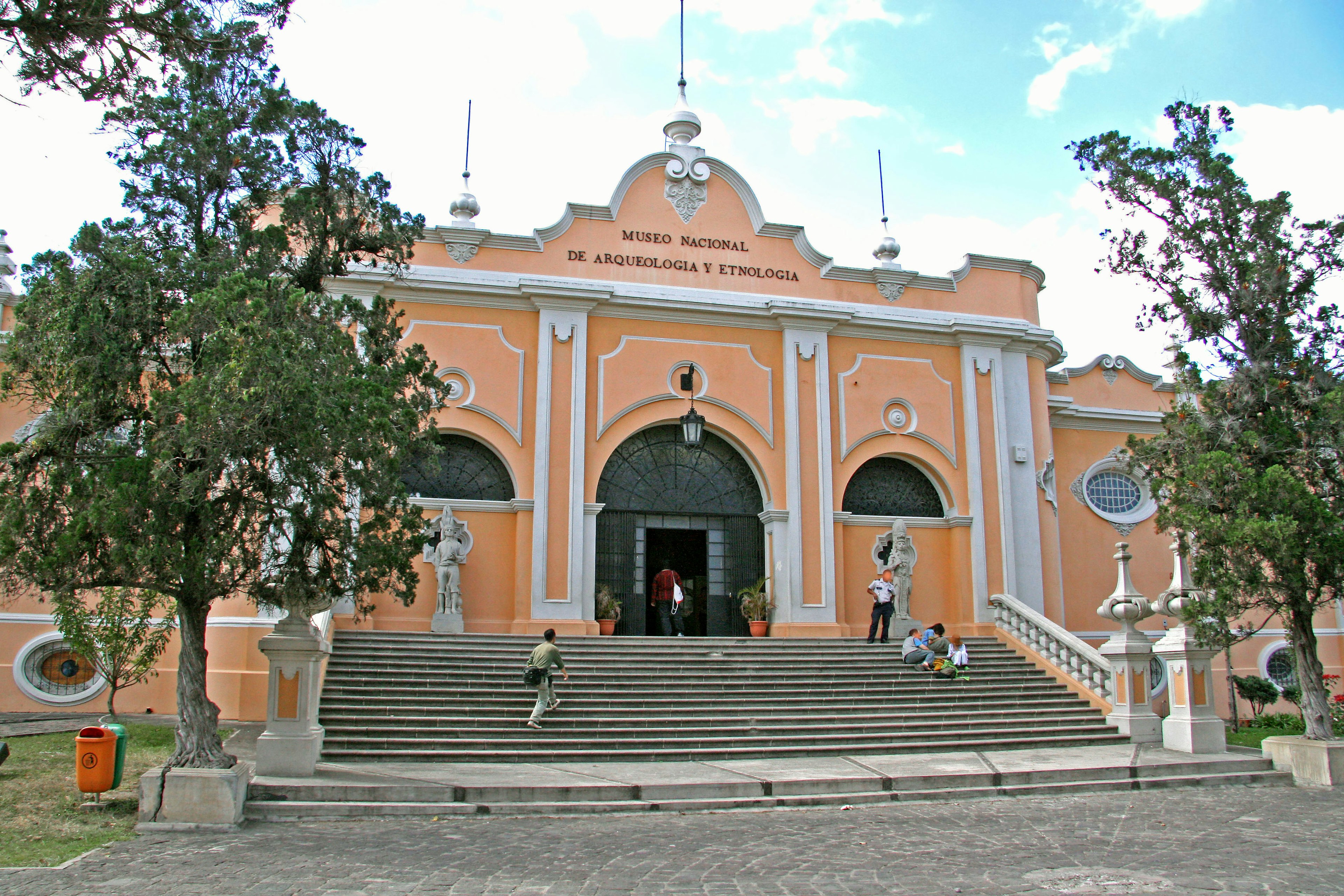 front view of a historic building with orange walls and grand staircase