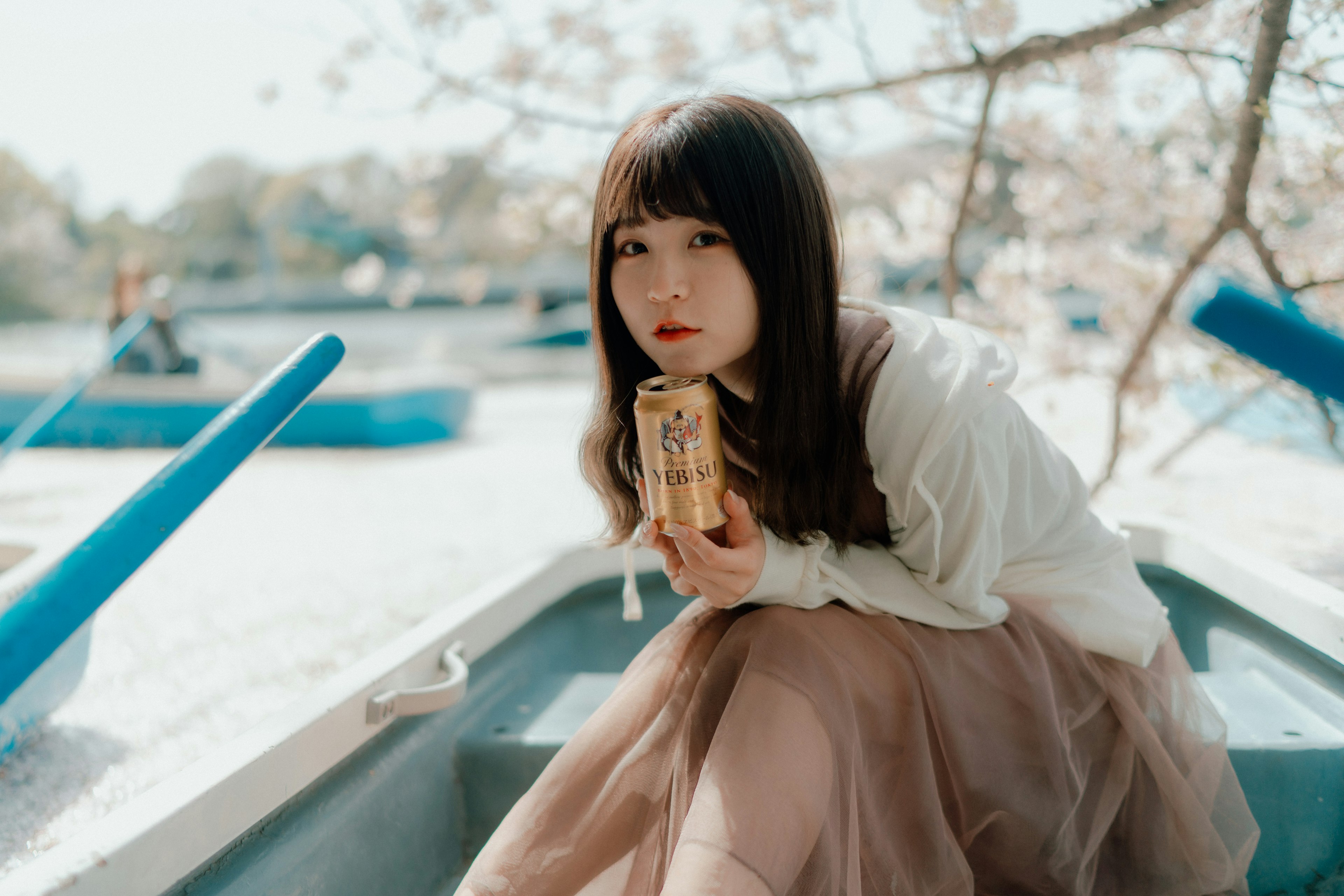 桜の木の下で缶を持つ女性のポートレート