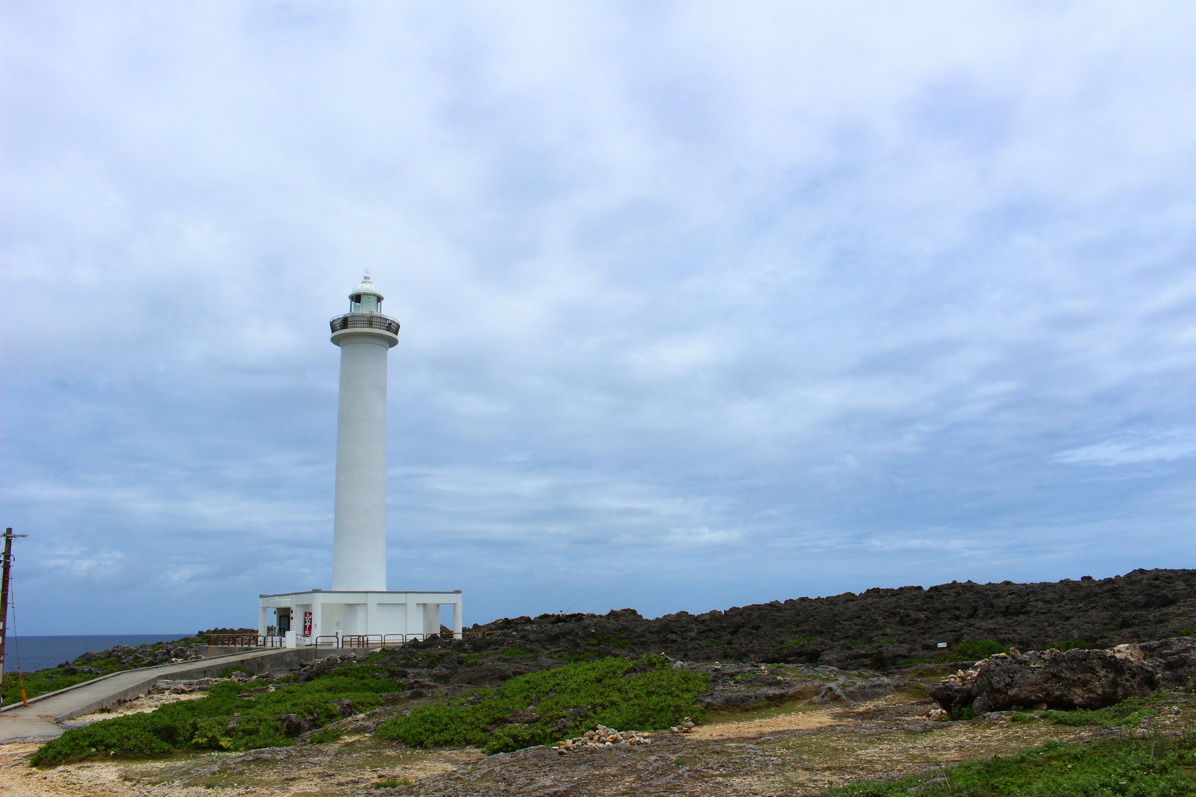 Faro blanco junto al mar bajo un cielo nublado