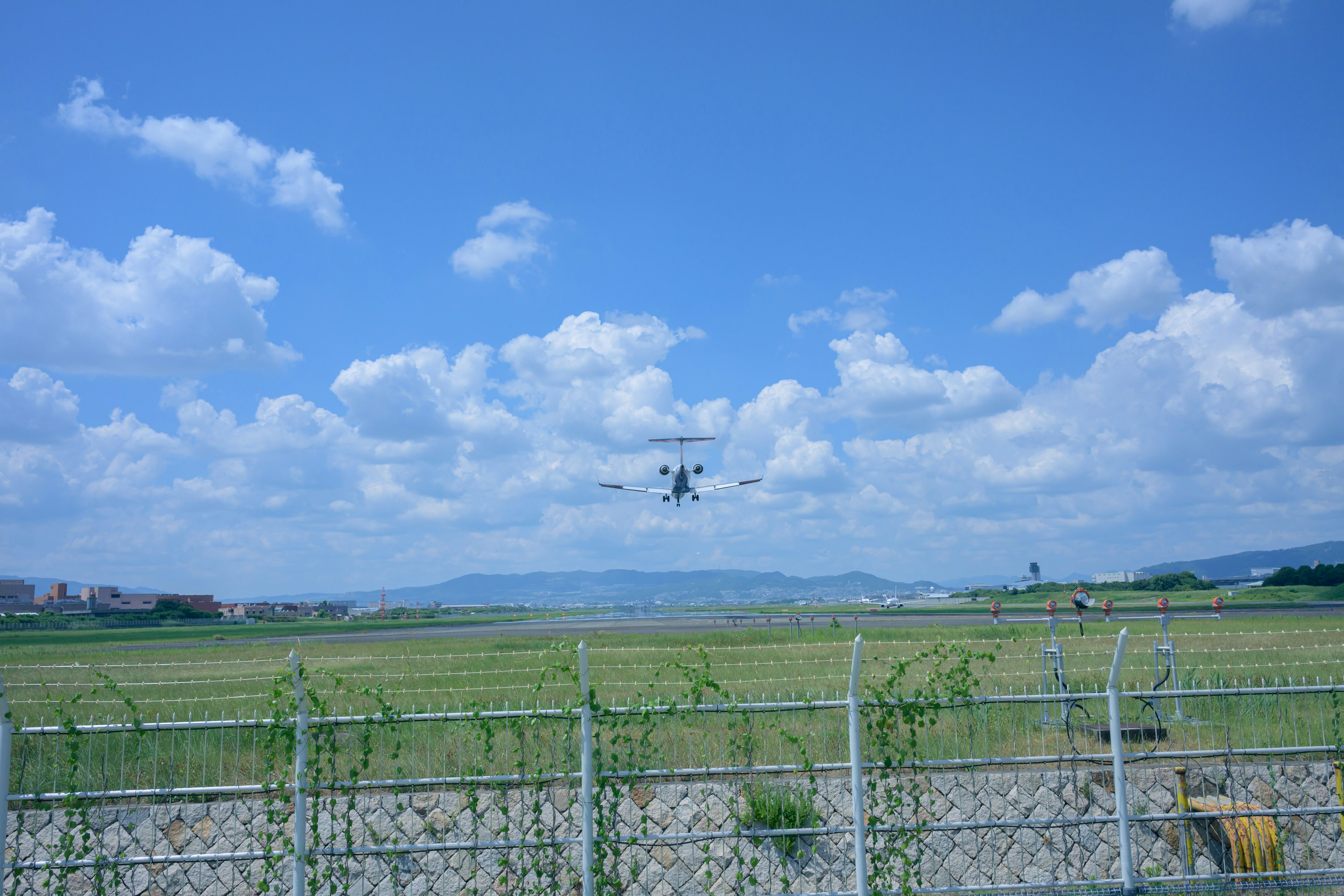 Drone che vola sotto un cielo blu con ampie campagne verdi