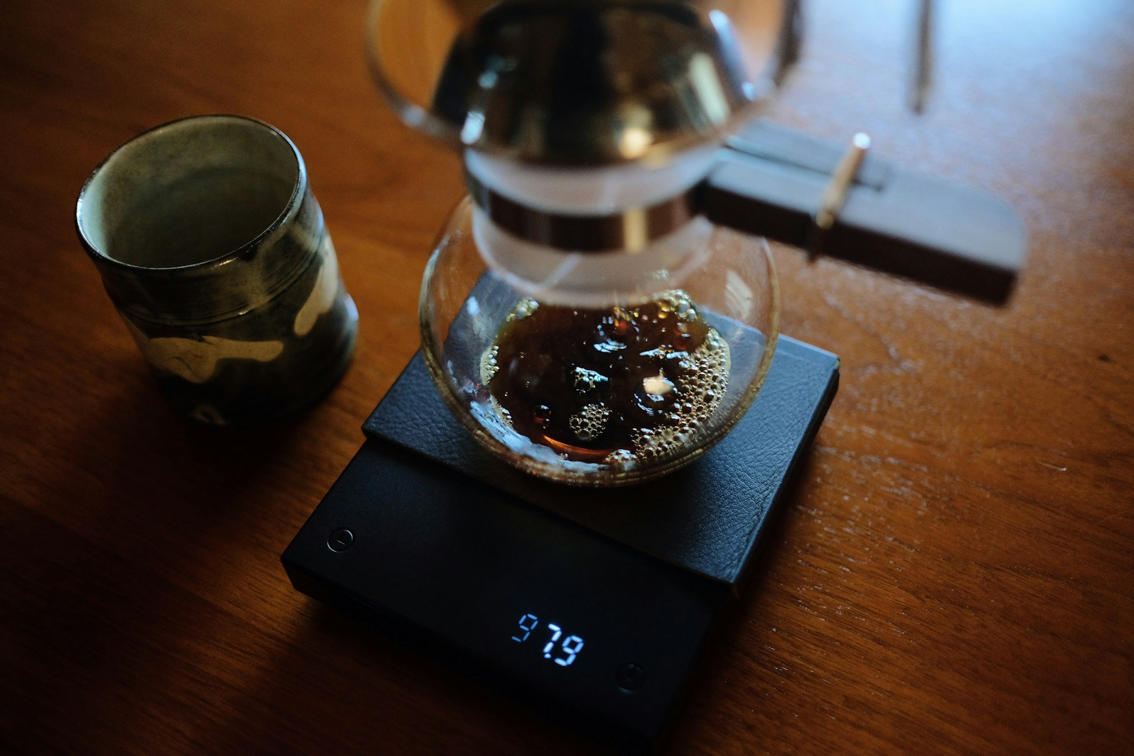 Cafetière à siphon en train de préparer du café sur une balance numérique avec du café moulu