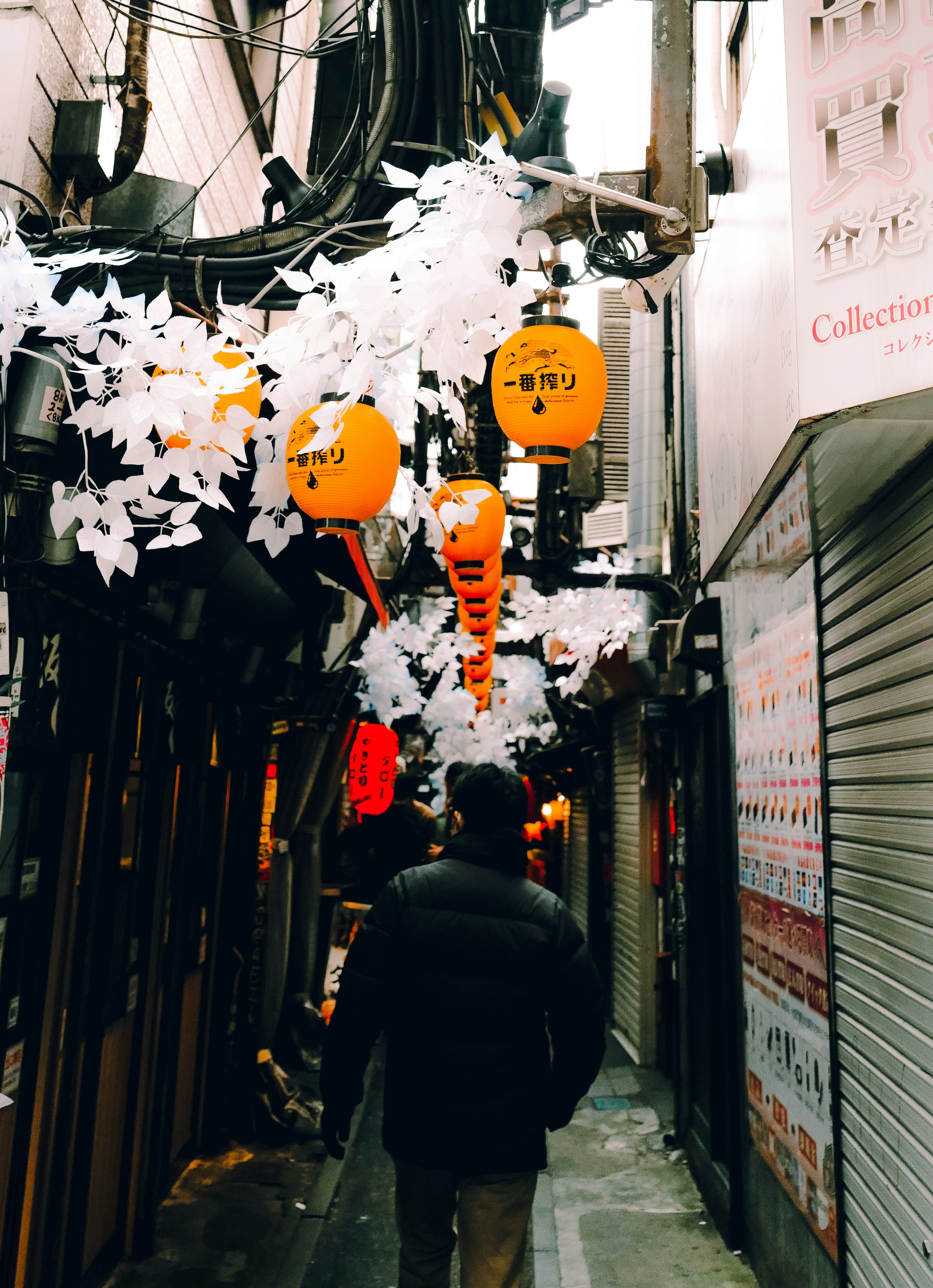 狭い路地に飾られたオレンジ色の提灯と白い装飾が特徴の風景