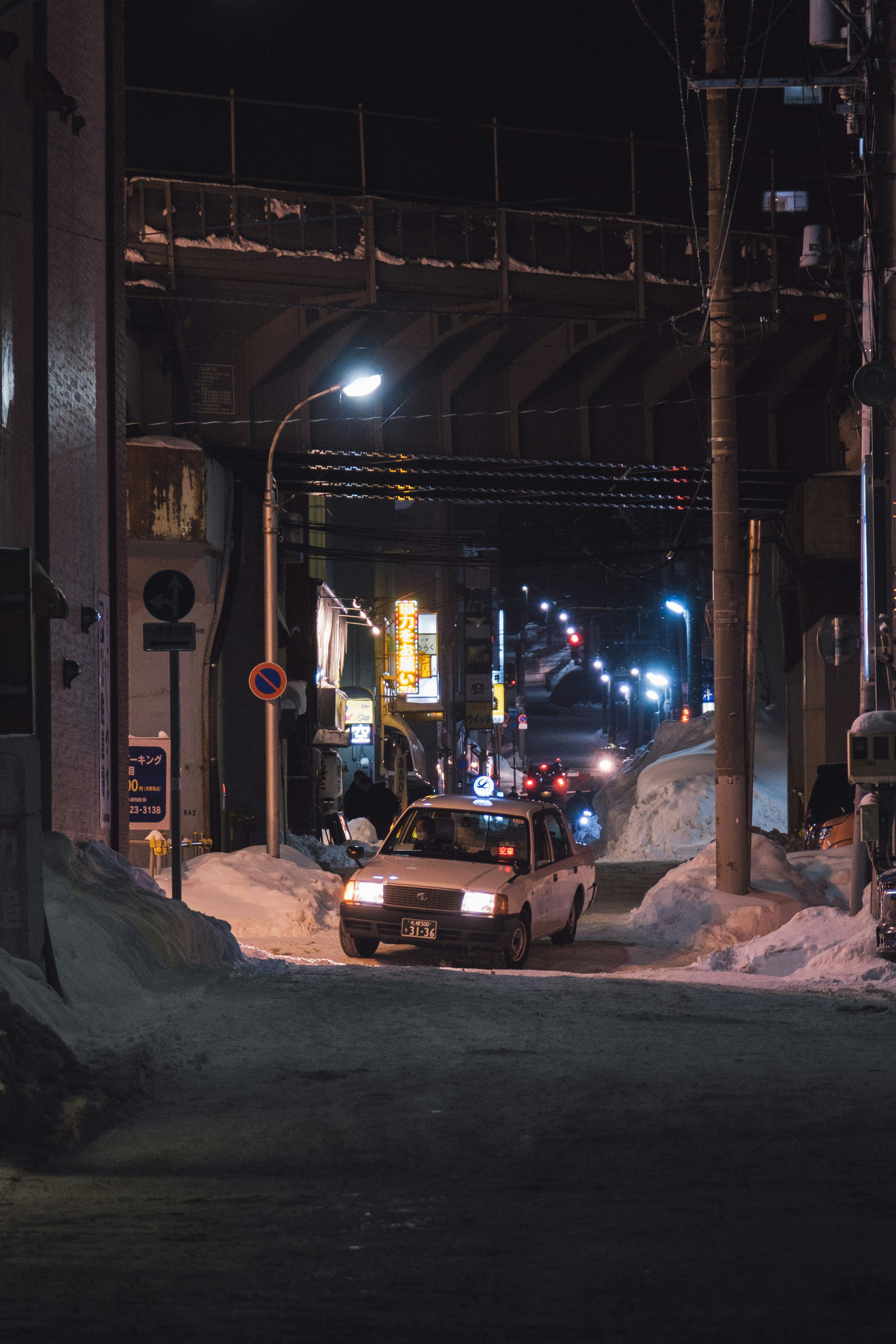 雪に覆われた夜の街道を走る車と街灯