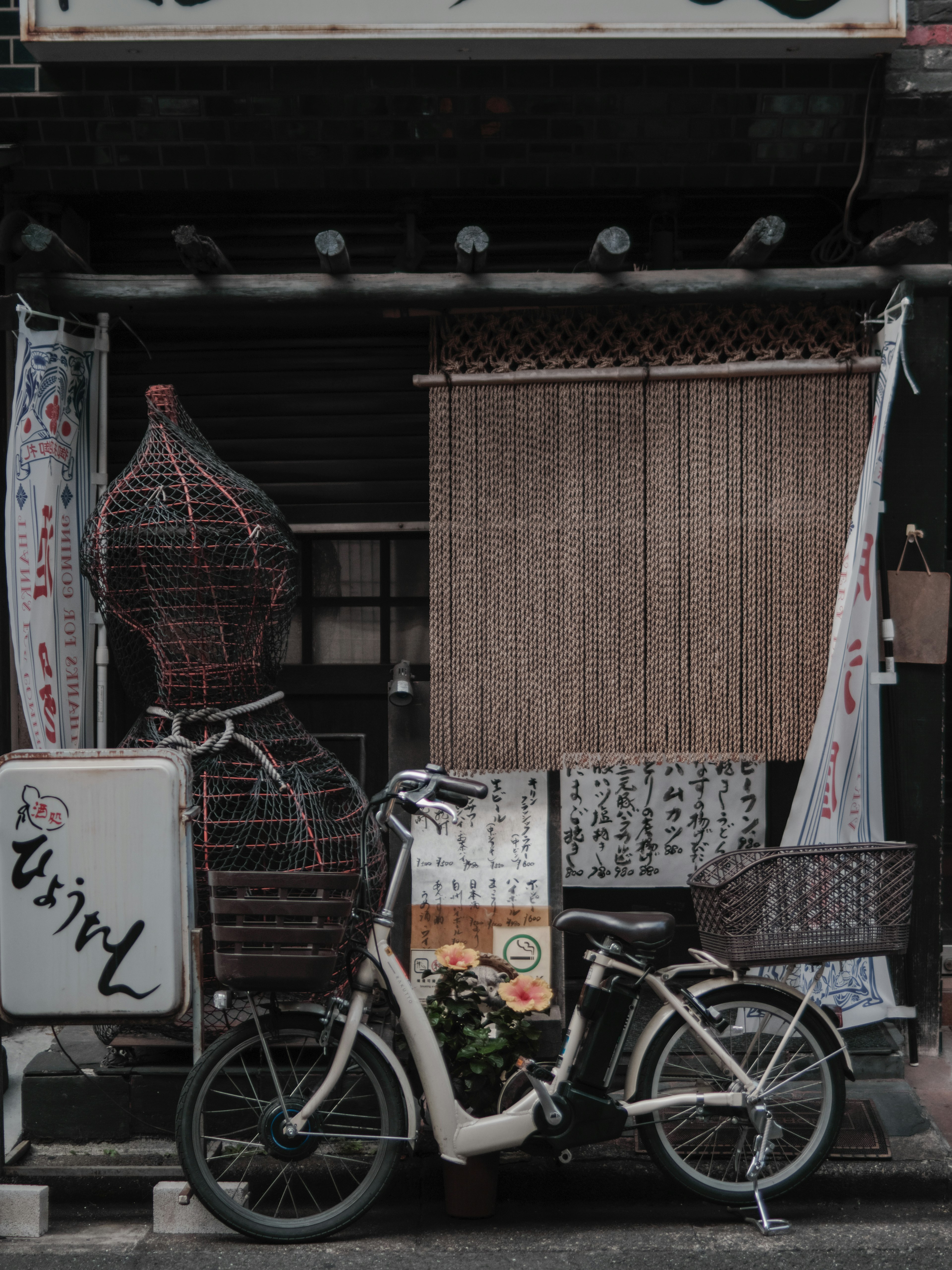 自行车停在老店前面，背景有竹子装饰