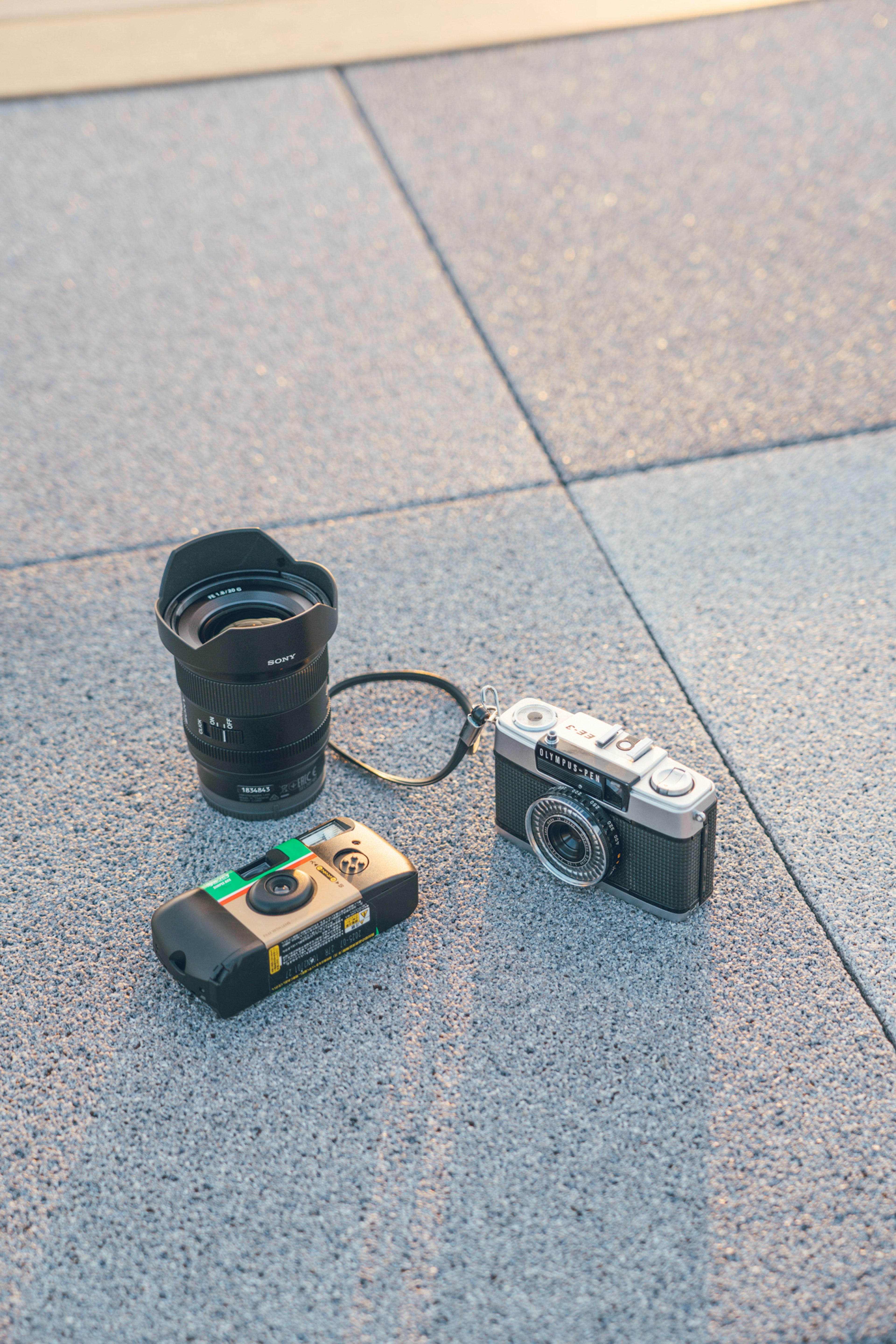 Un appareil photo argentique et un appareil photo numérique avec un objectif posés sur une surface texturée