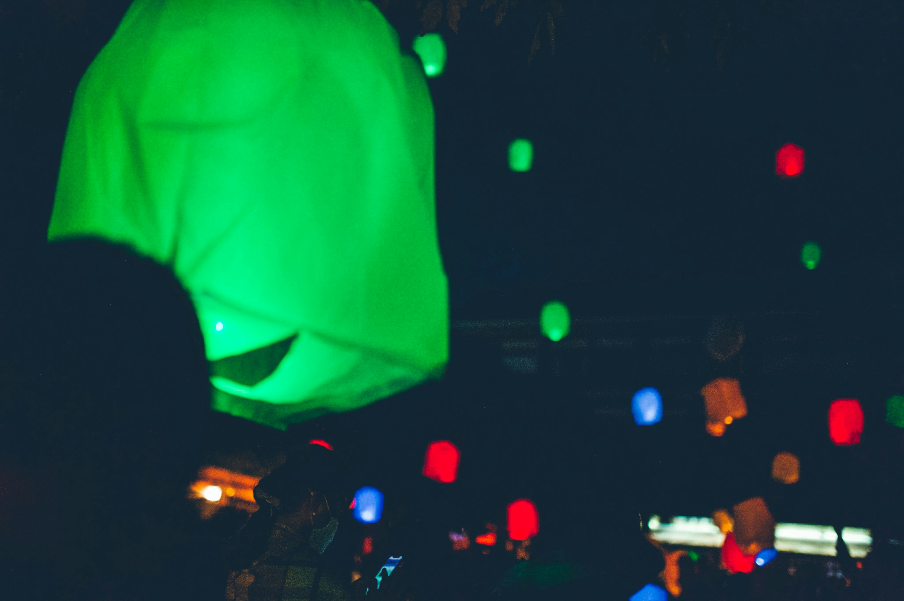 Lampu warna-warni mengapung di langit malam dengan cahaya hijau