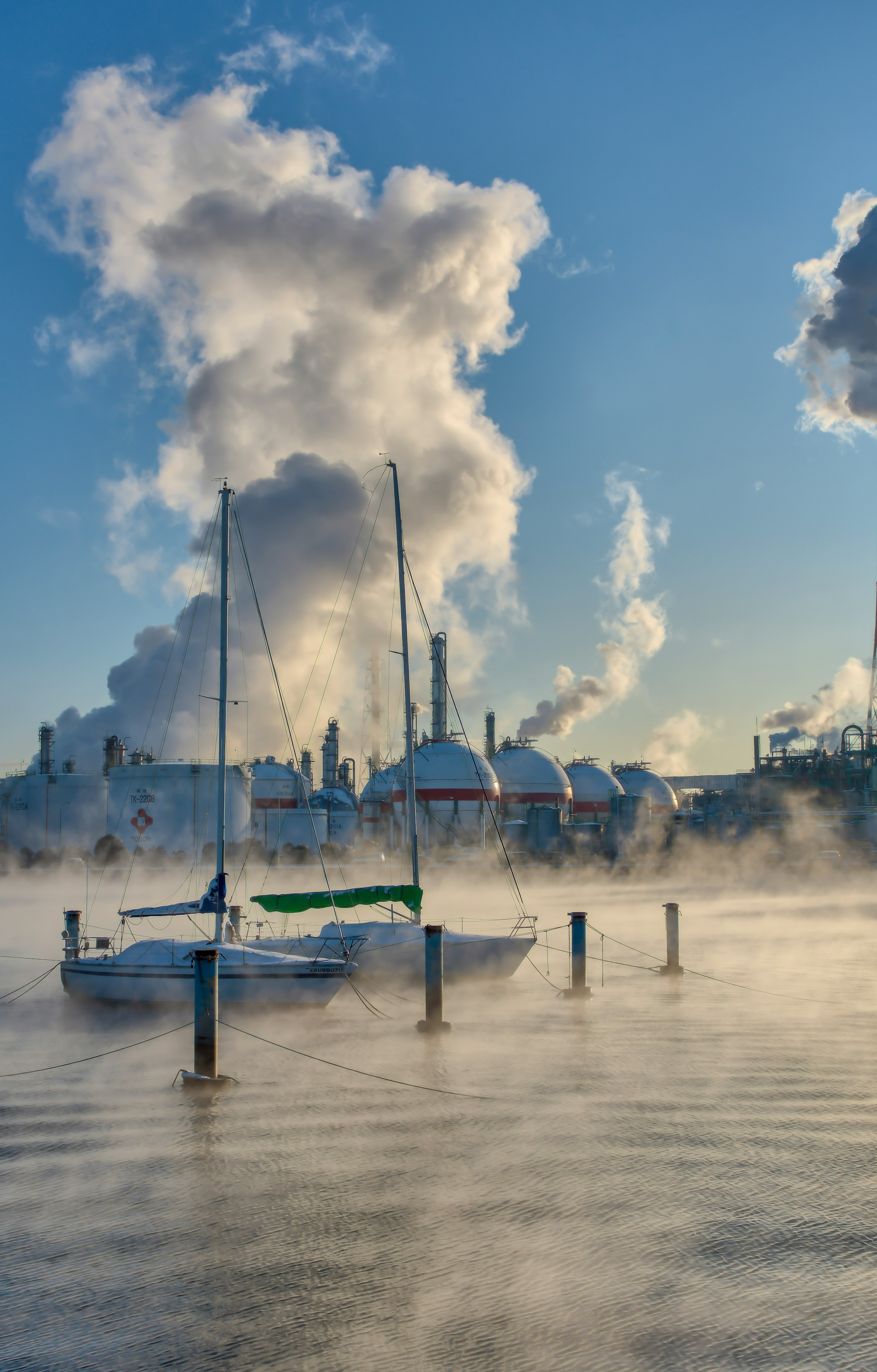 Un yacht émergeant de la brume avec de la fumée s'échappant des bâtiments industriels