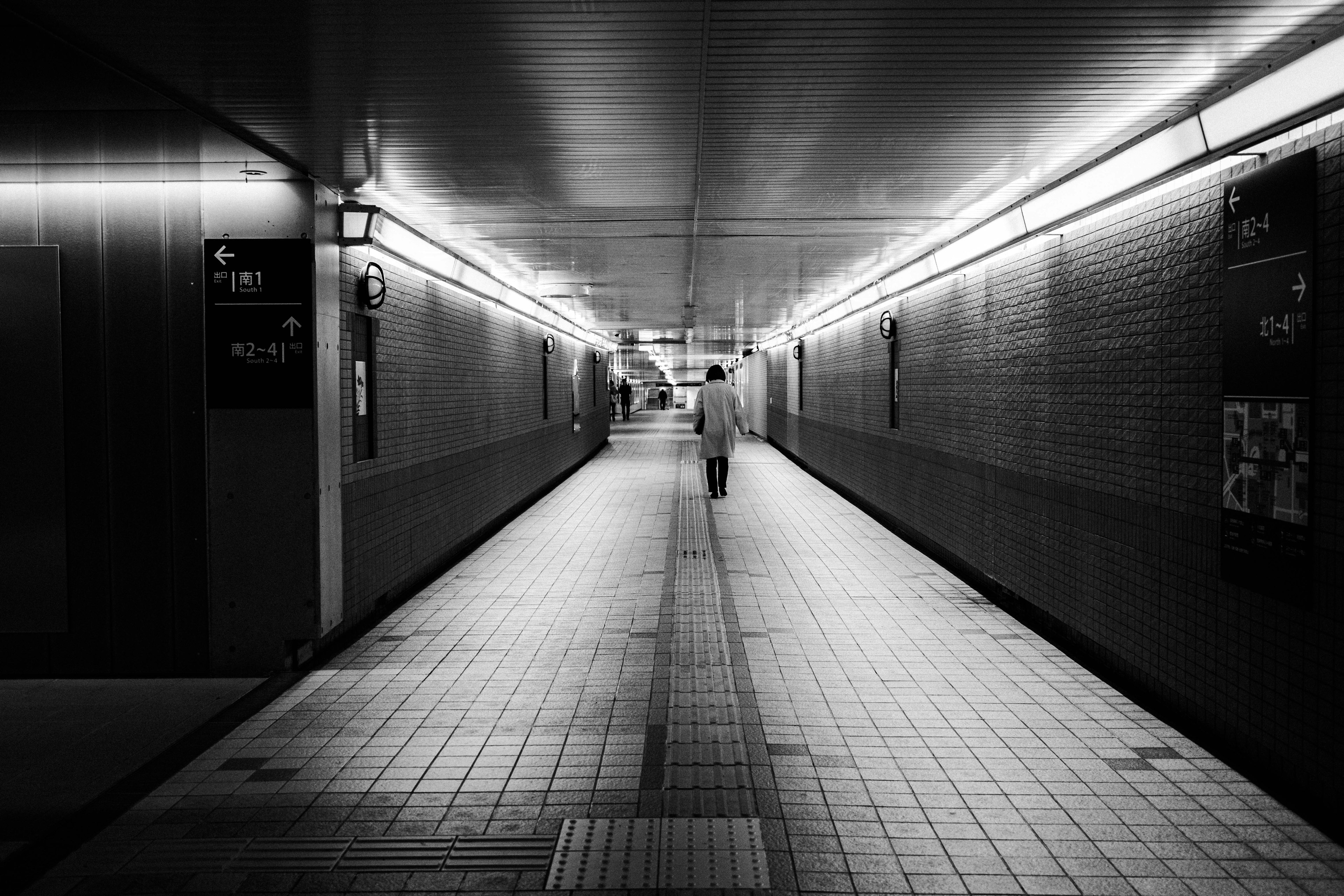 Una persona caminando en un pasillo subterráneo en blanco y negro