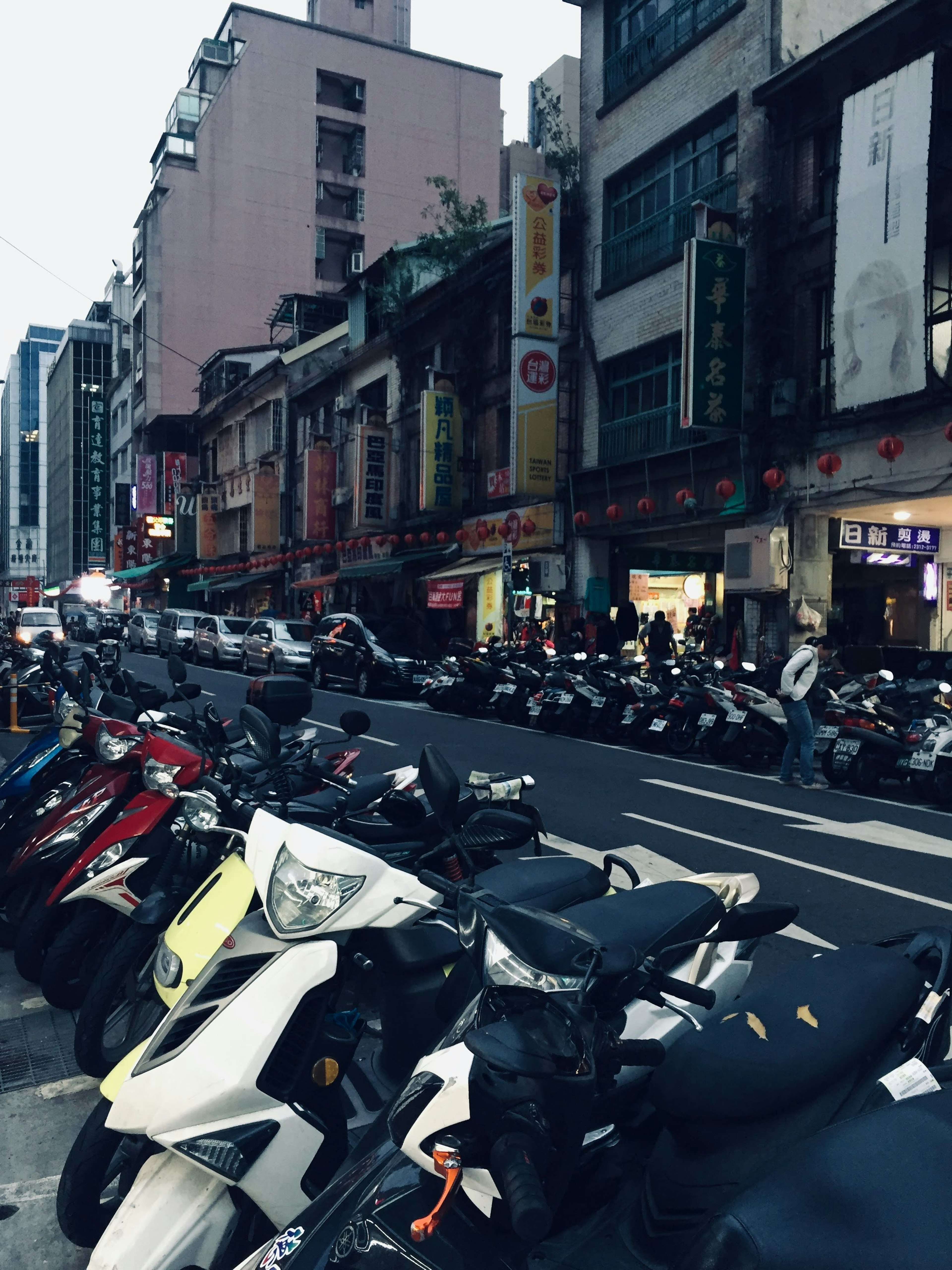 Scooters and motorcycles lined up on a city street at night