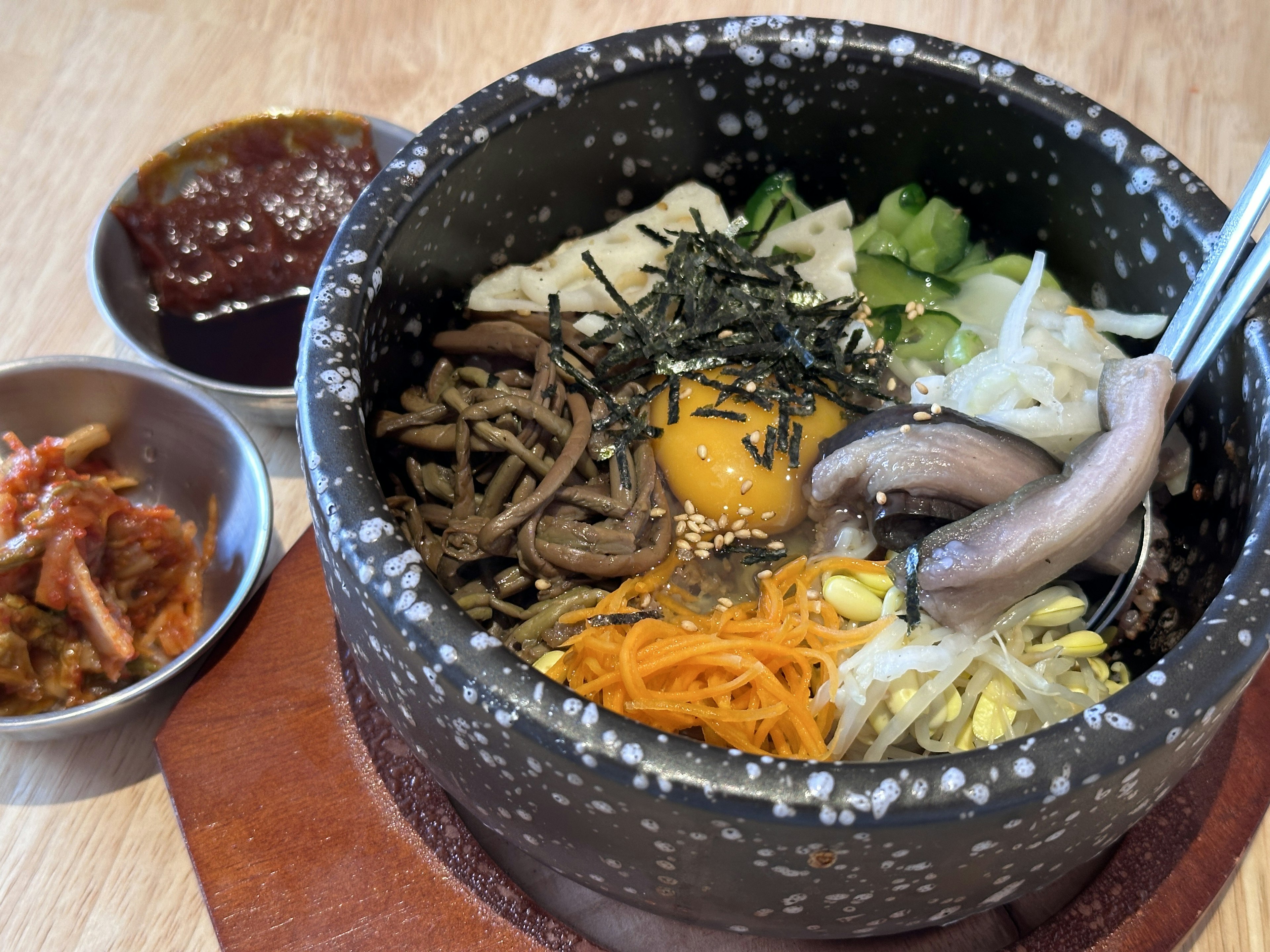 Bibimbap serviert in einer Steinschale mit Gemüse und einem Ei