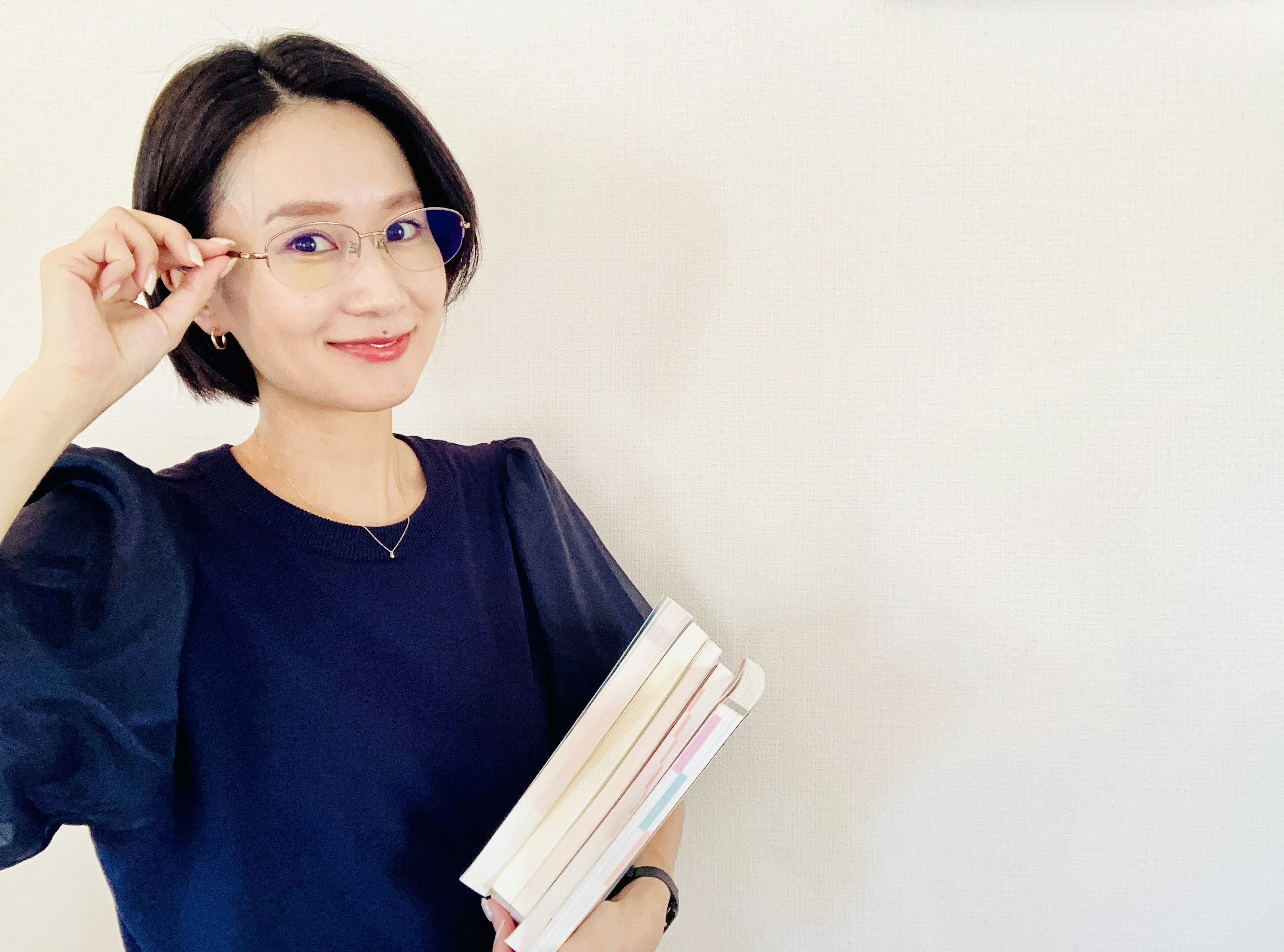 Mujer con blusa azul sonriendo mientras sostiene libros