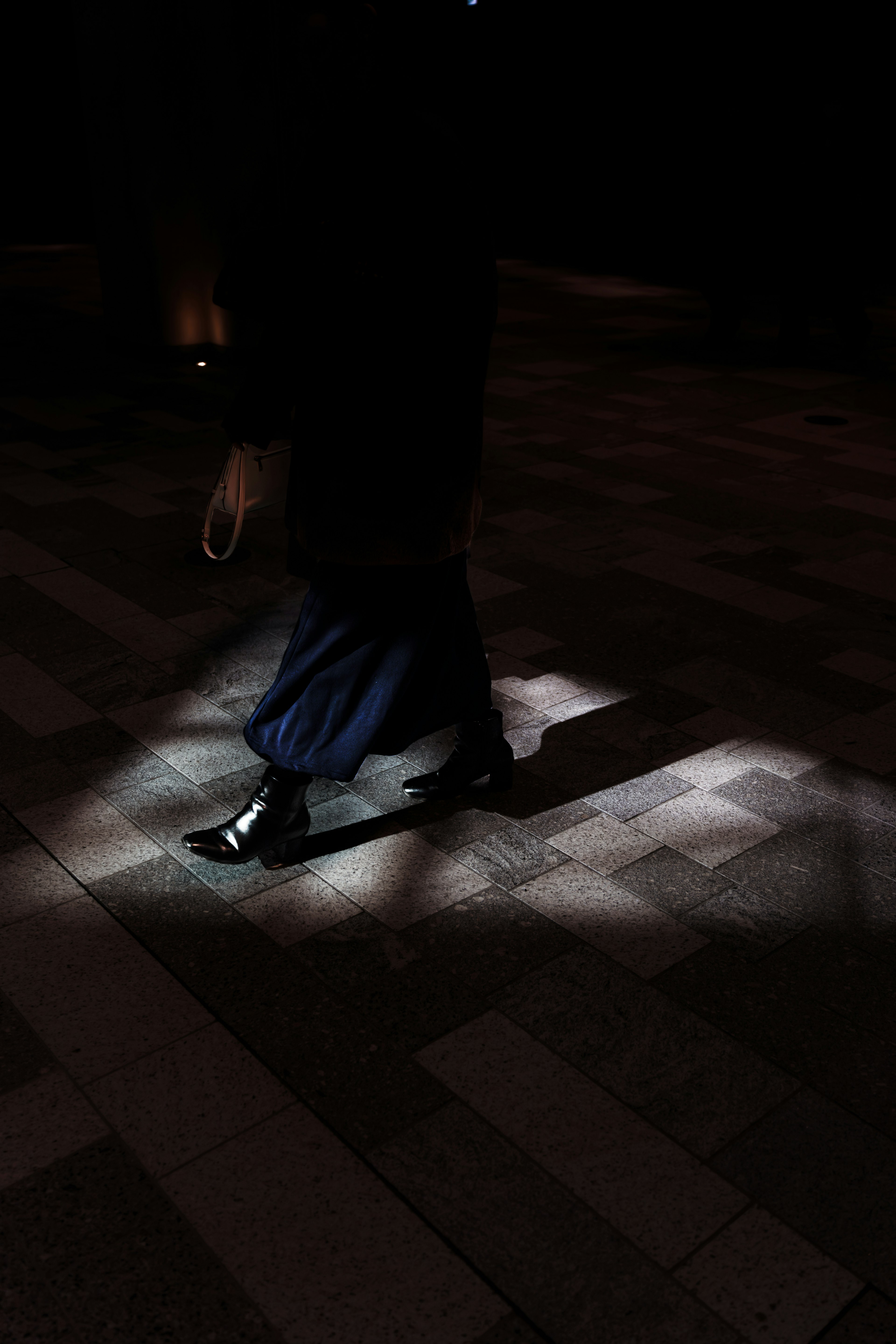 Persona caminando en un espacio oscuro iluminado por luz en el suelo