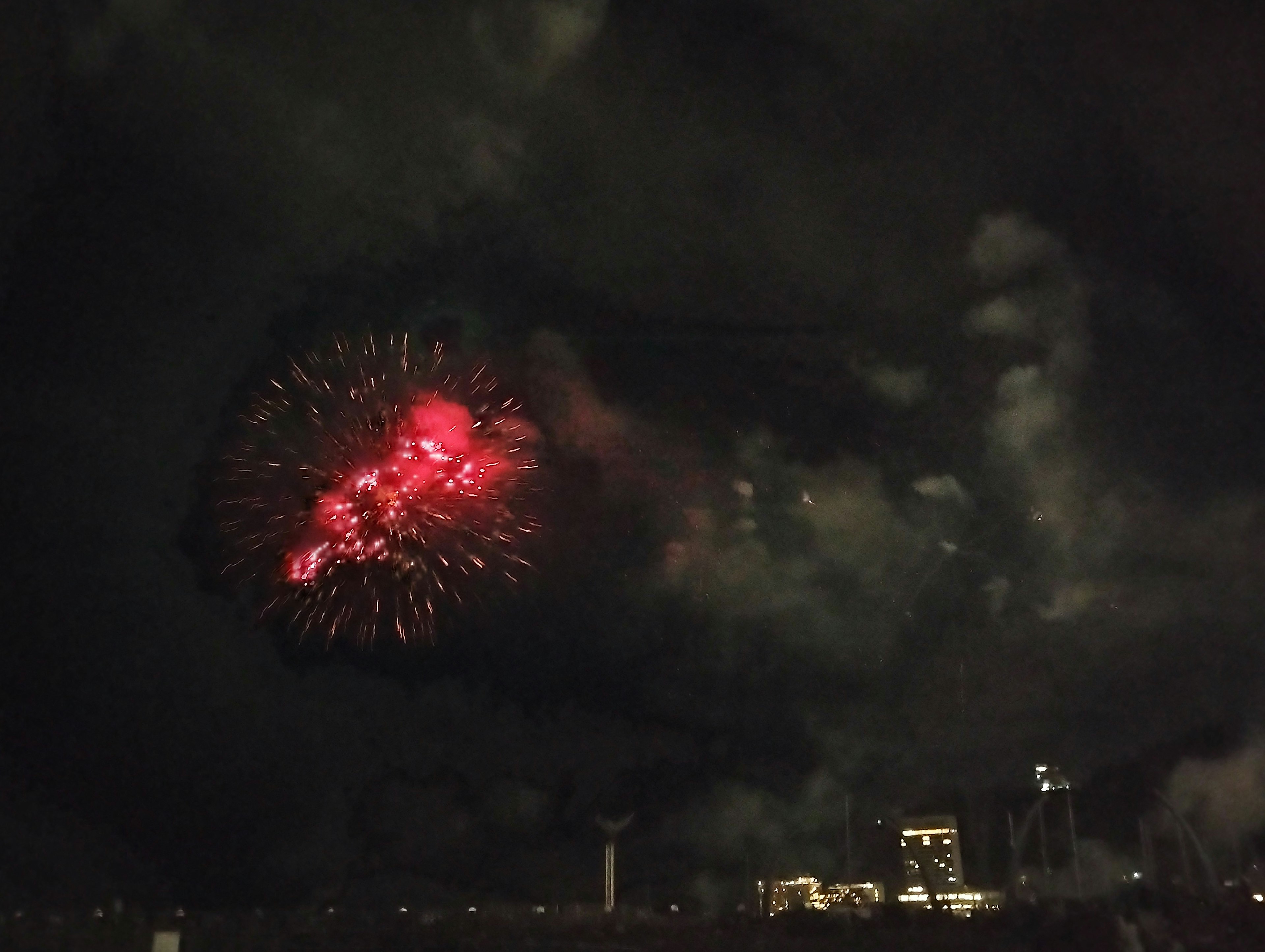 Rote Feuerwerke, die am Nachthimmel mit dunklen Wolken explodieren