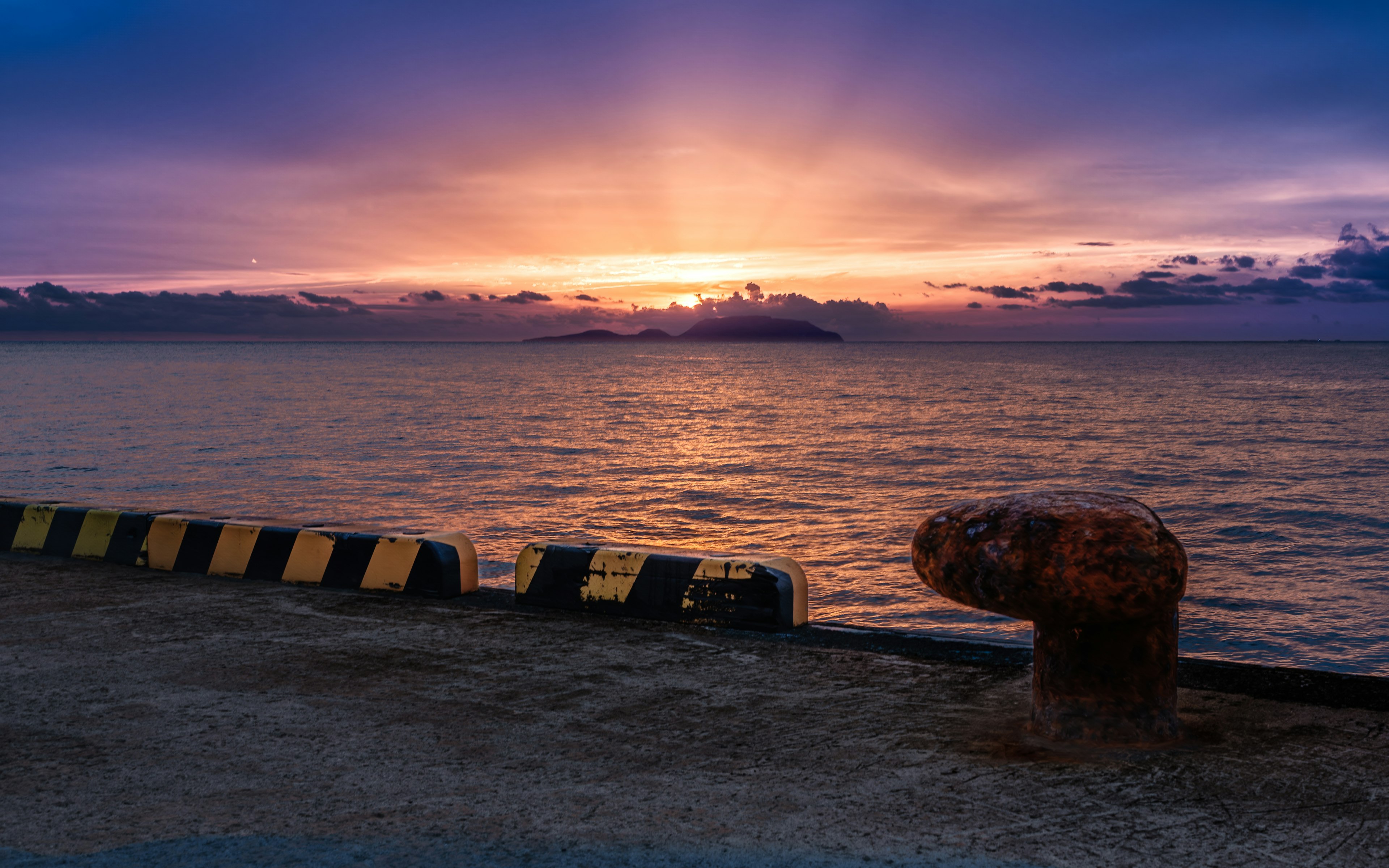 Küstenlandschaft mit Sonnenuntergang, der sich im Wasser spiegelt gelb-schwarze Barriere und Felsmerkmale