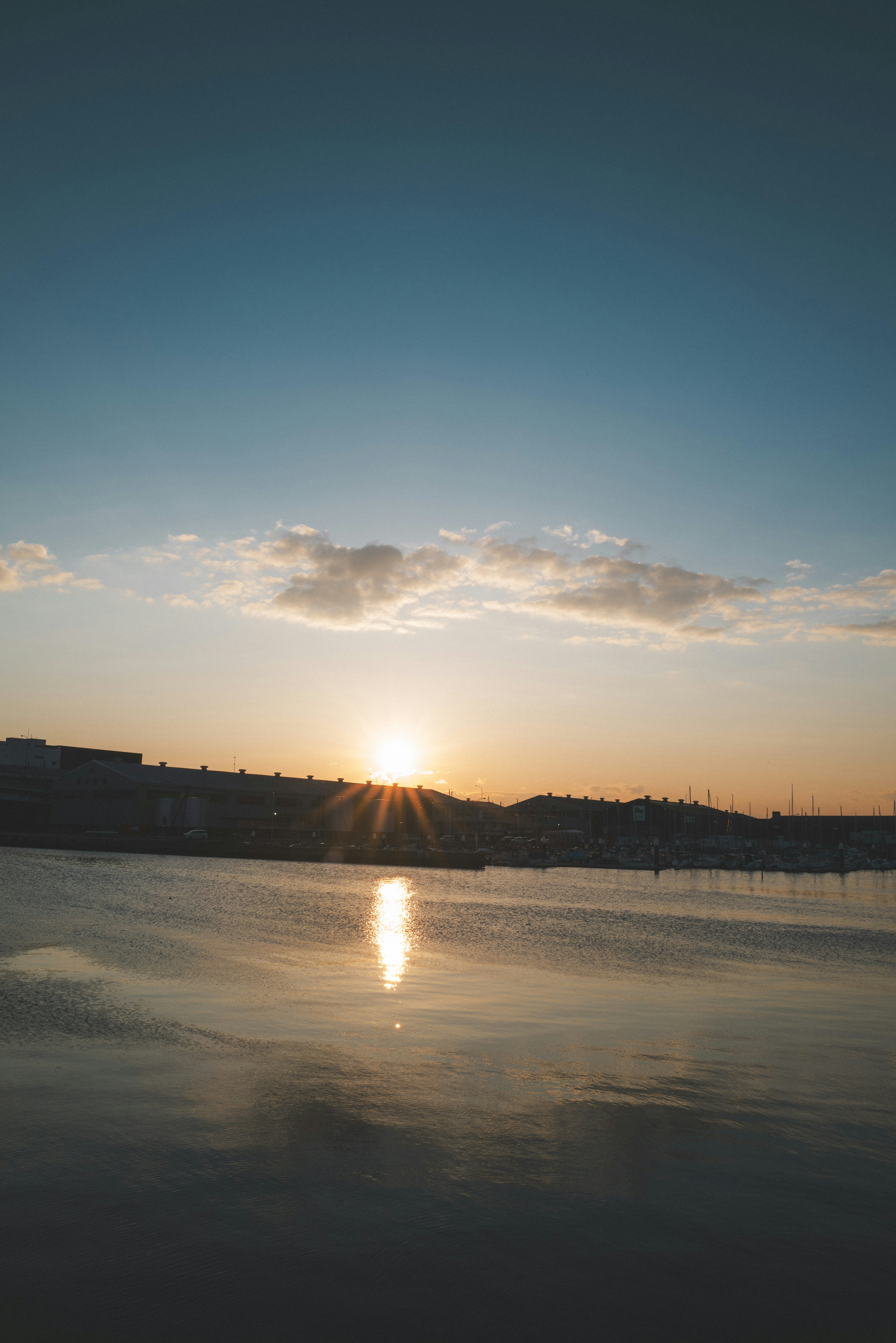 Schöne Landschaft mit Sonnenuntergang, der sich auf dem Wasser des Sees spiegelt, mit blauem Himmel