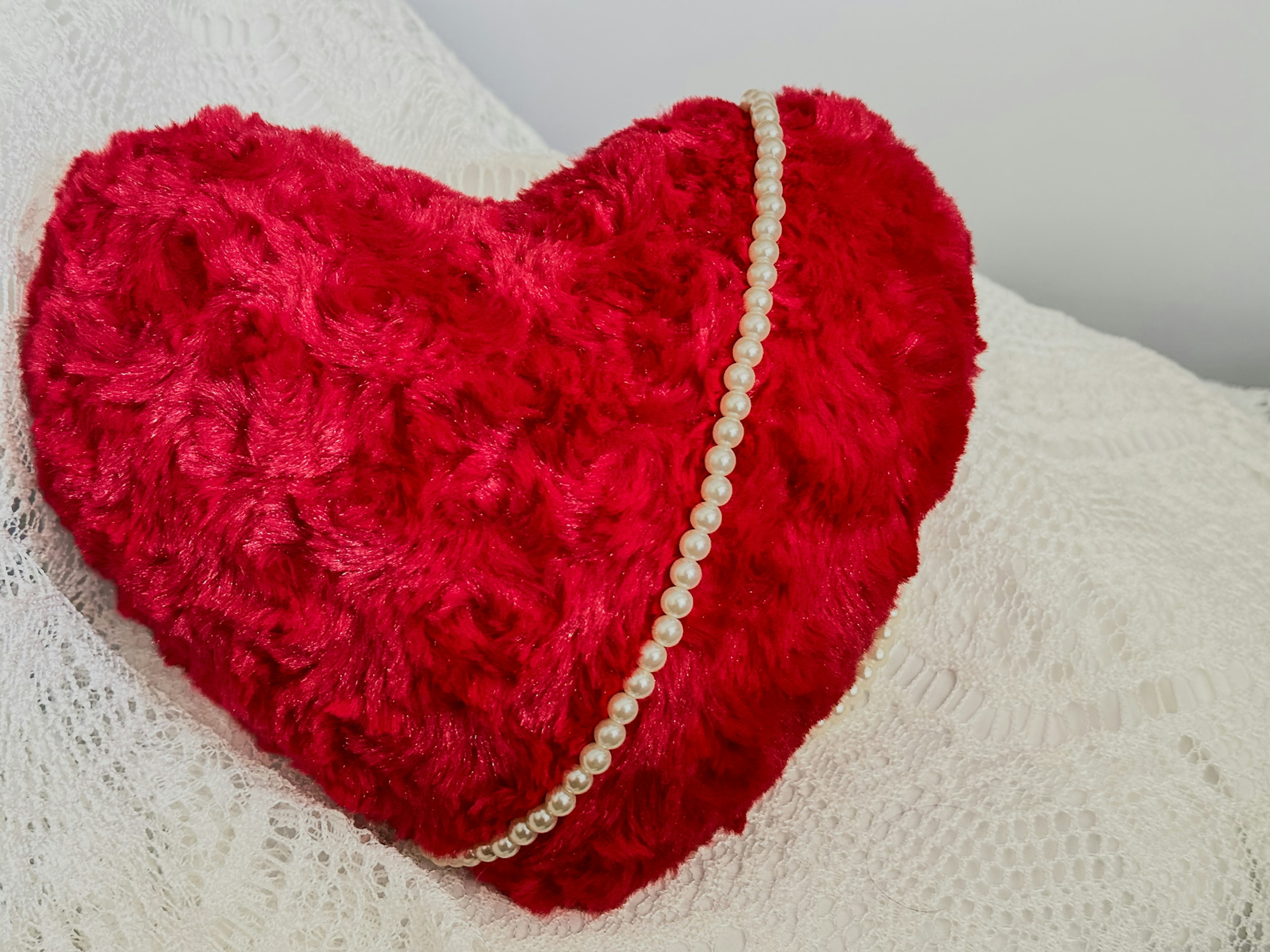 Red heart-shaped pillow with pearl embellishment