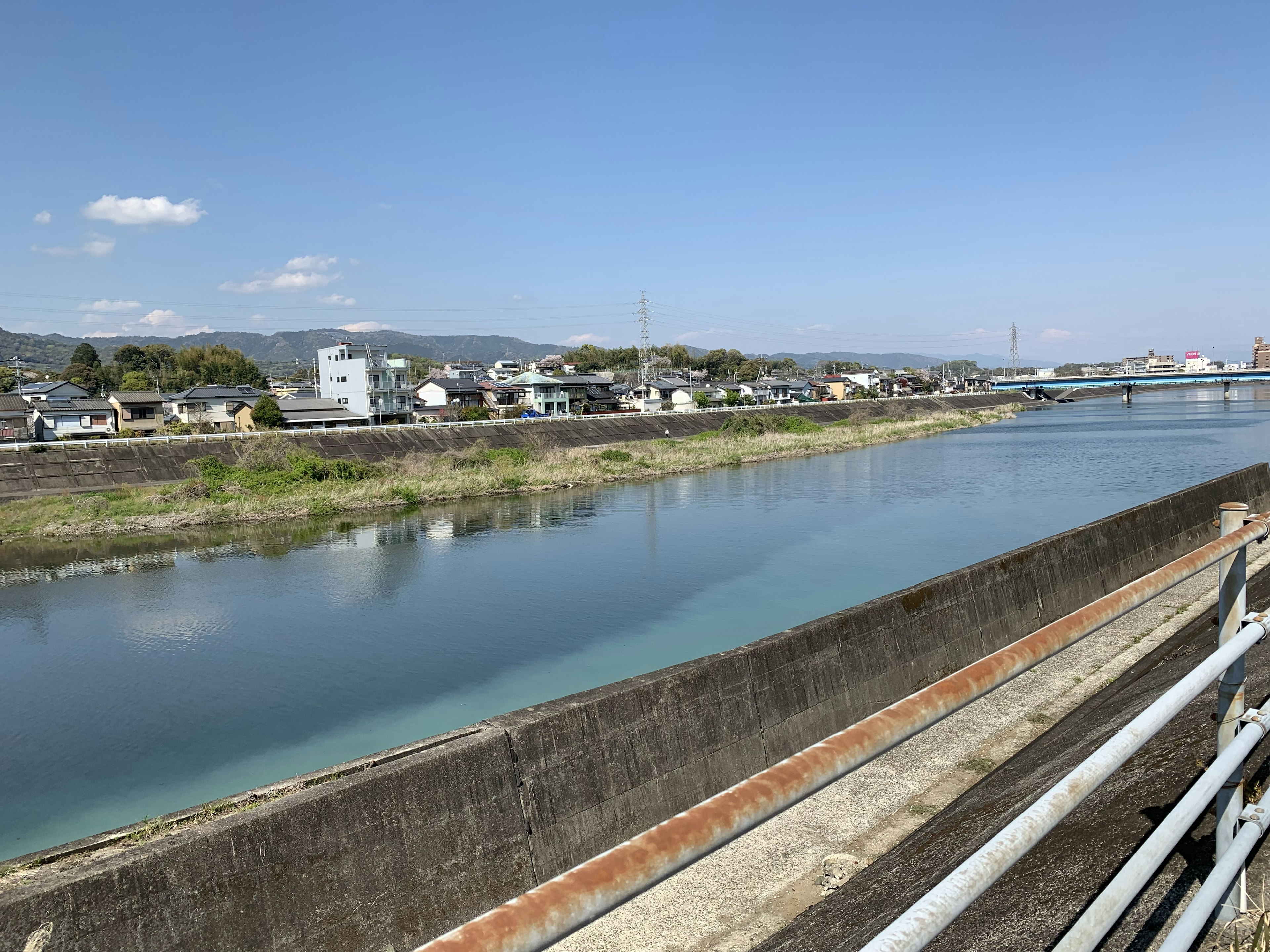 A serene riverside view with houses lined along the water under a blue sky