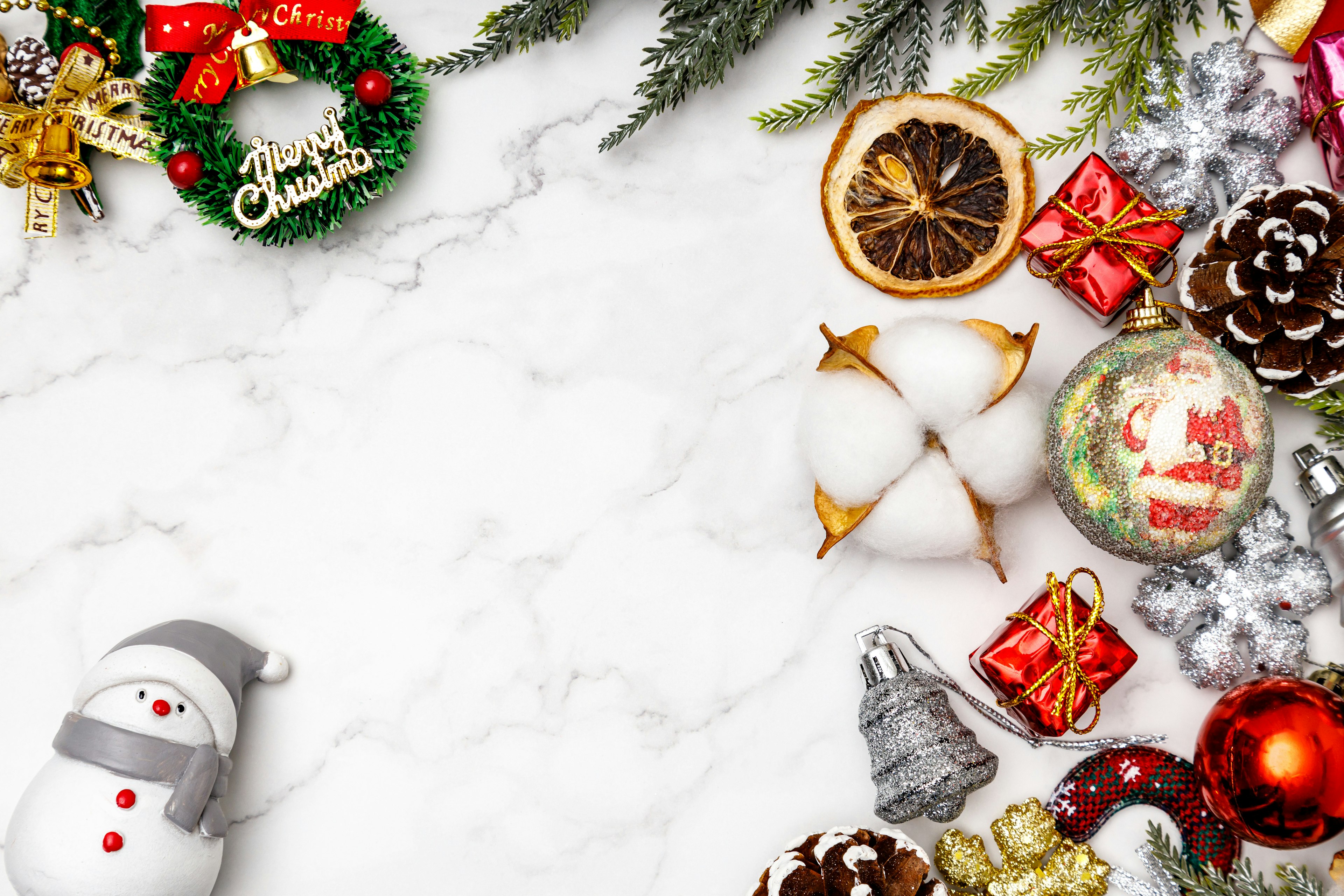 Christmas decorations and ornaments arranged on a white marble background featuring a snowman and a wreath