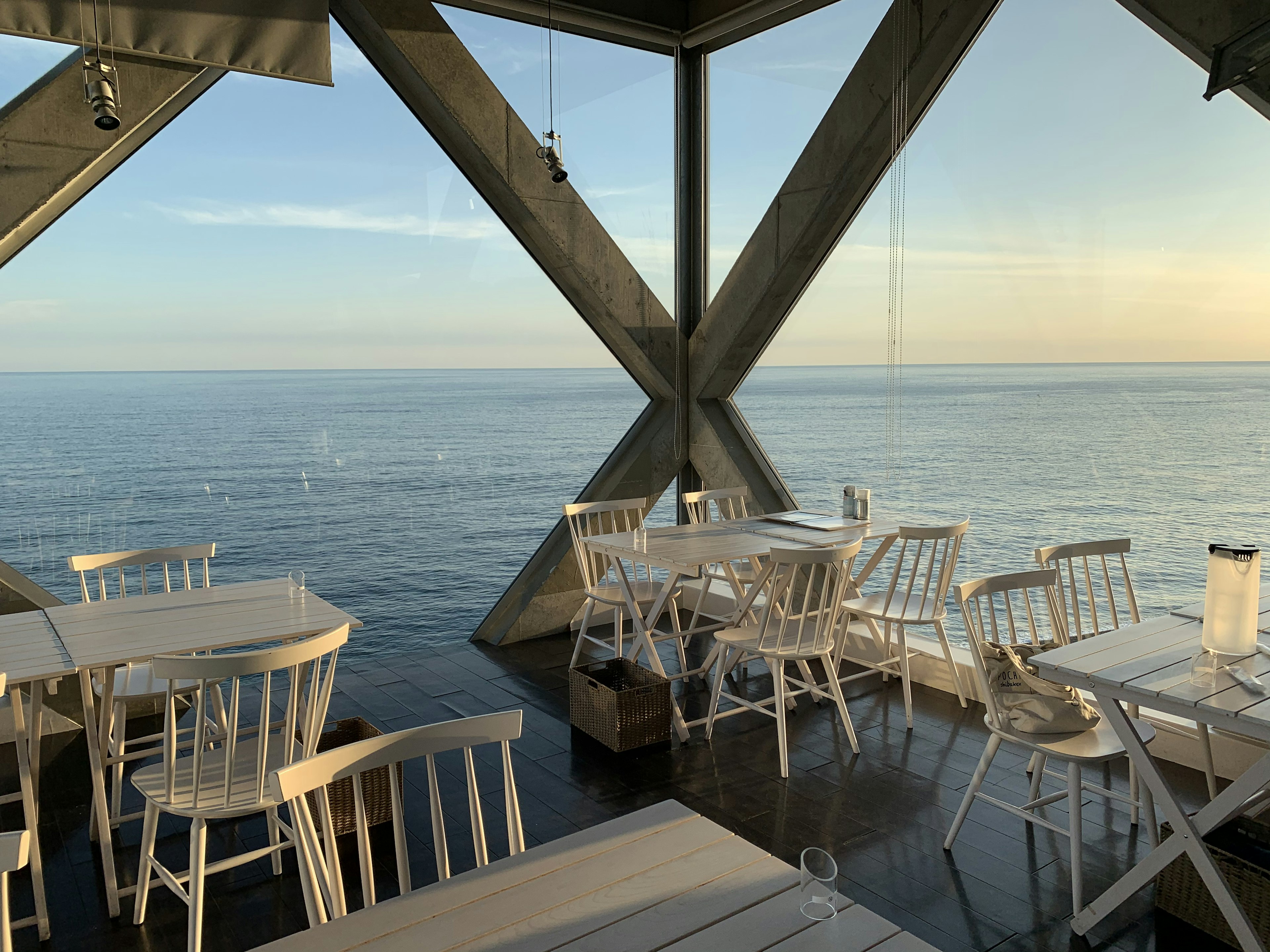 Intérieur moderne de restaurant surplombant la mer avec des tables et des chaises blanches