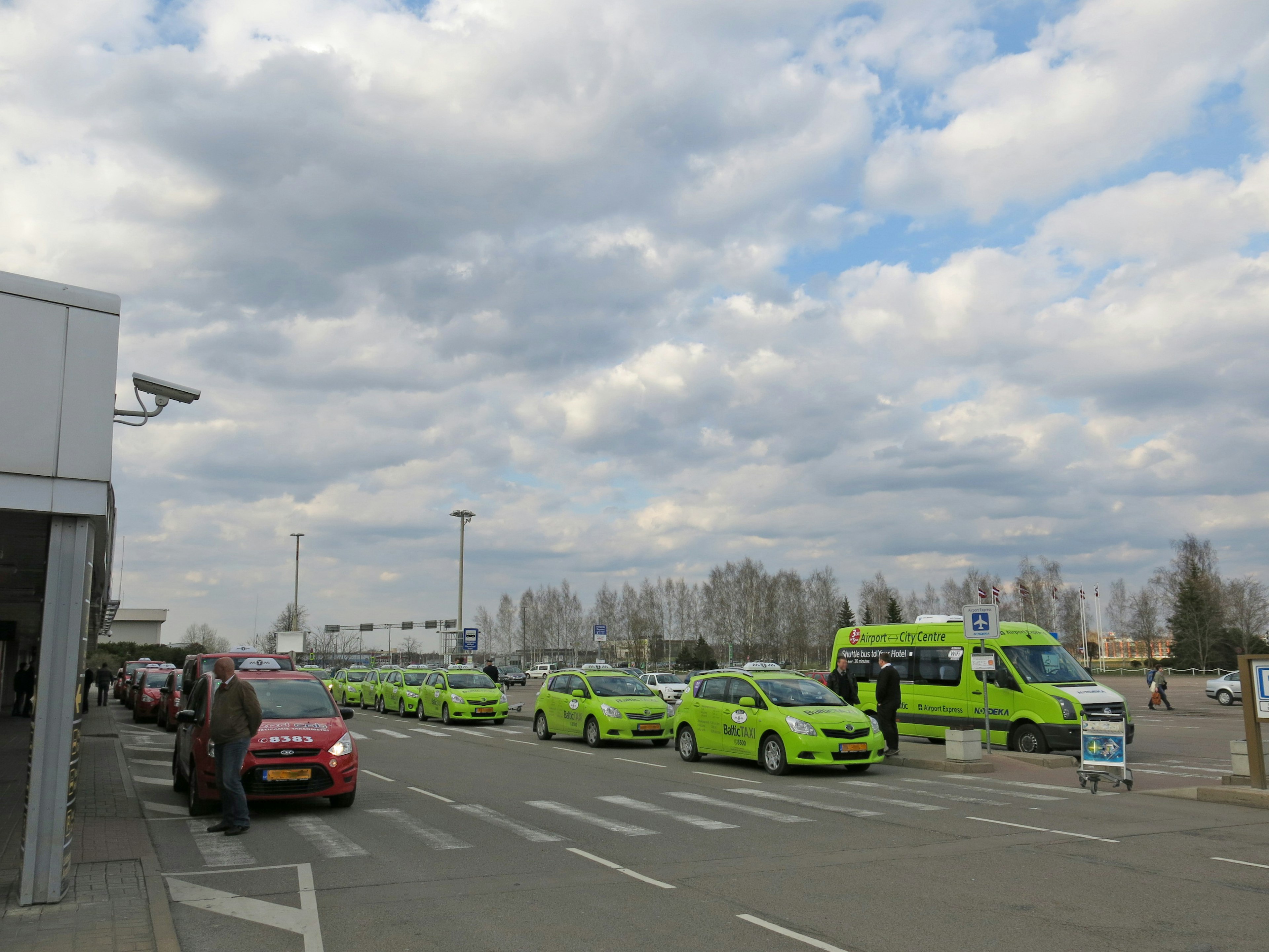 Taxis verdes en fila en un stand de taxis del aeropuerto bajo un cielo nublado