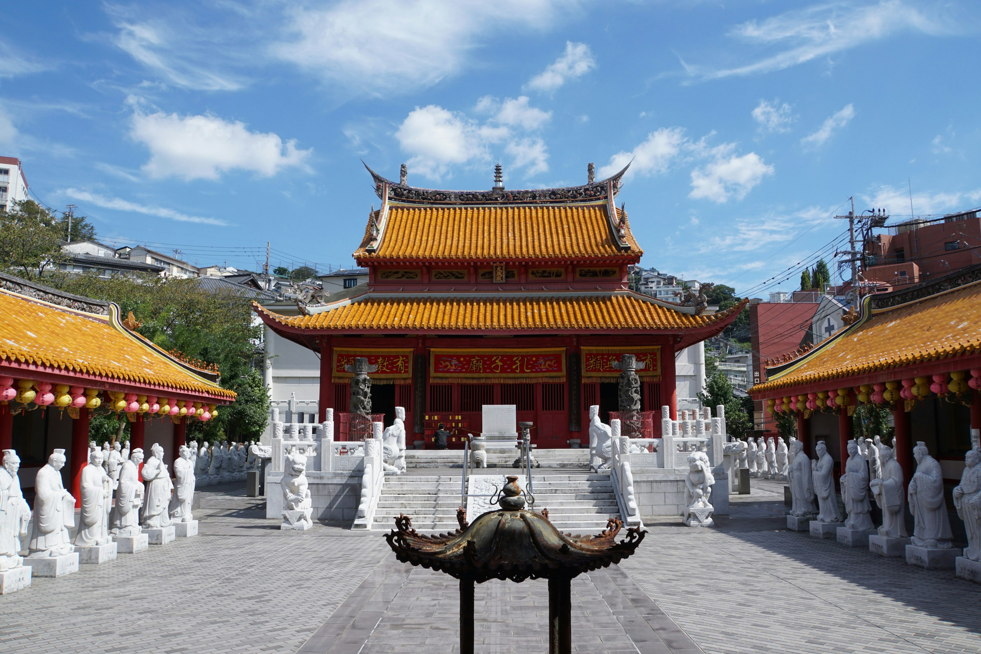 Tempel mit goldenem Dach unter blauem Himmel umgeben von weißen Skulpturen