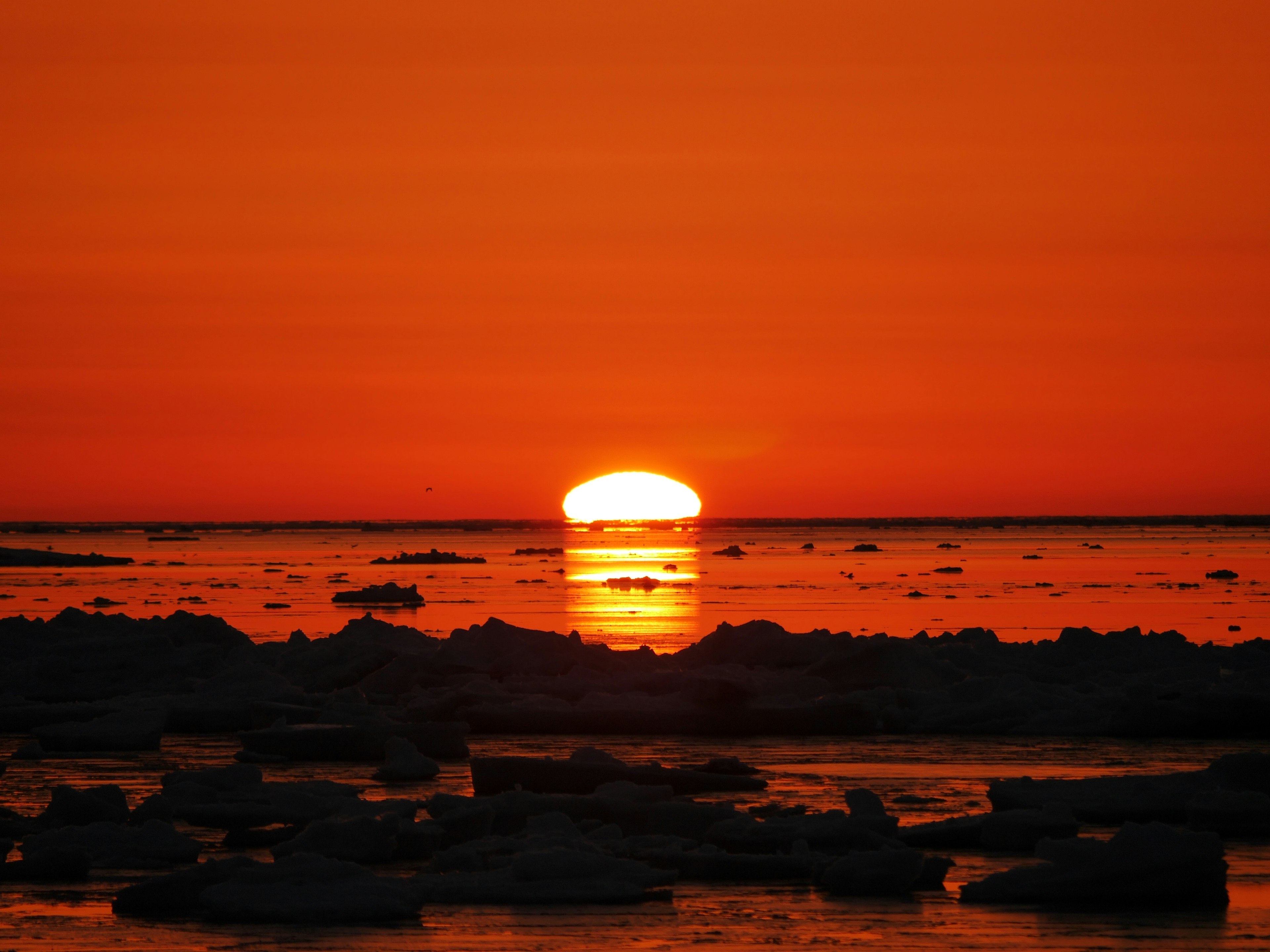 Sonnenuntergang über eisigen Gewässern mit orangefarbenem Himmel